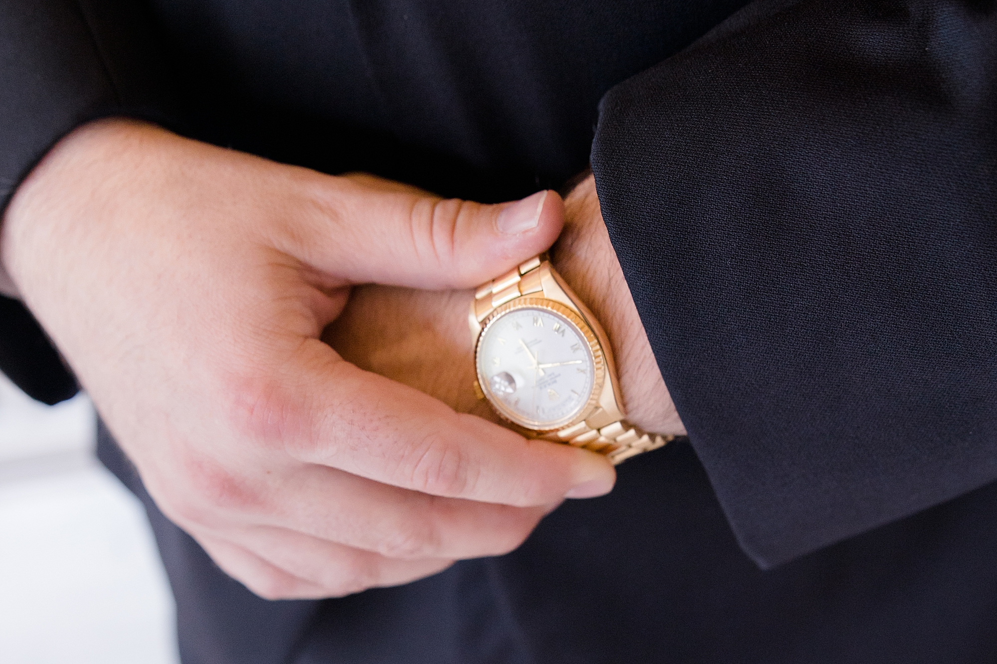 groom adjusts gold watch on wedding day