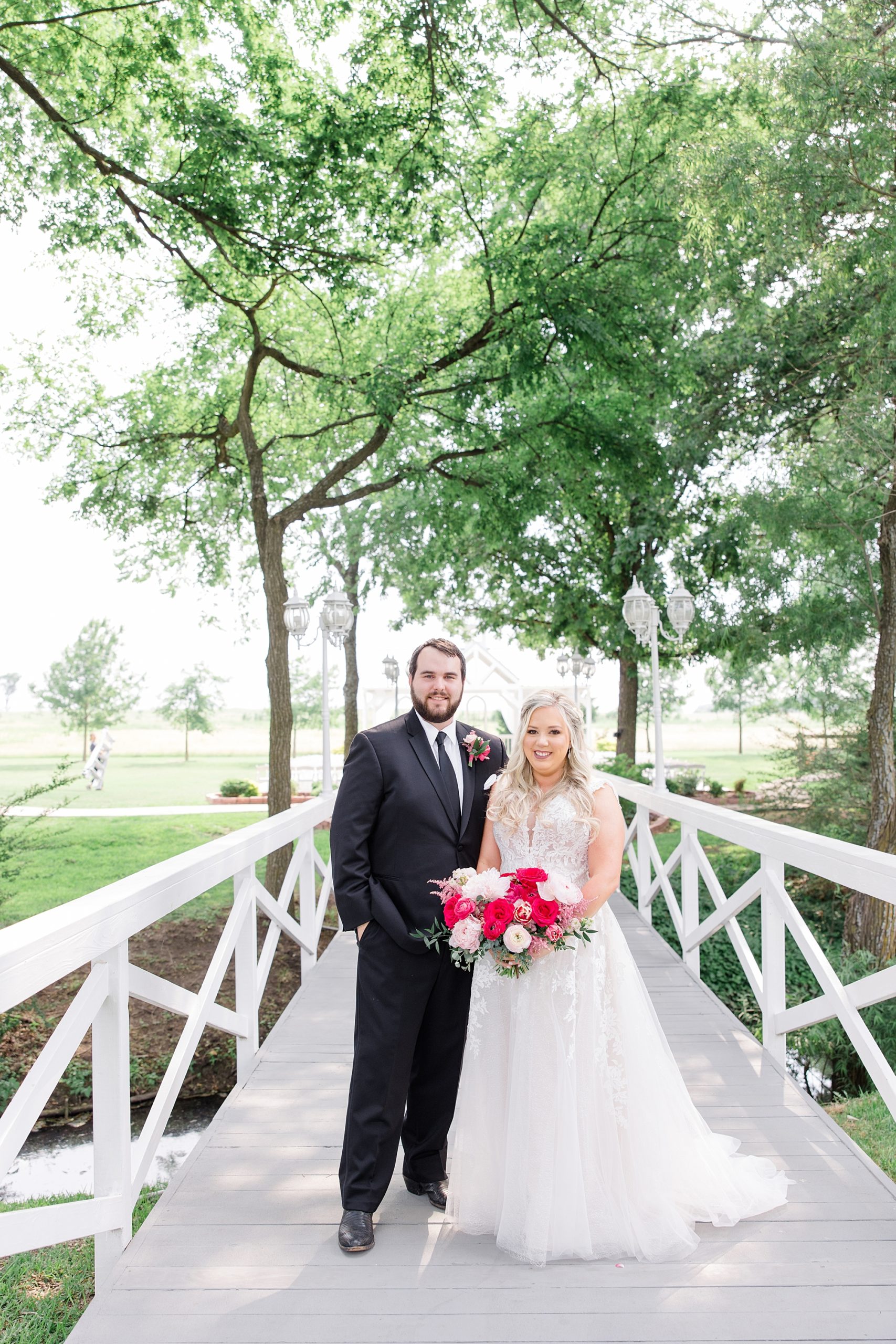 newlyweds stand on bride at Willow Creek while bride holds bright bouquet