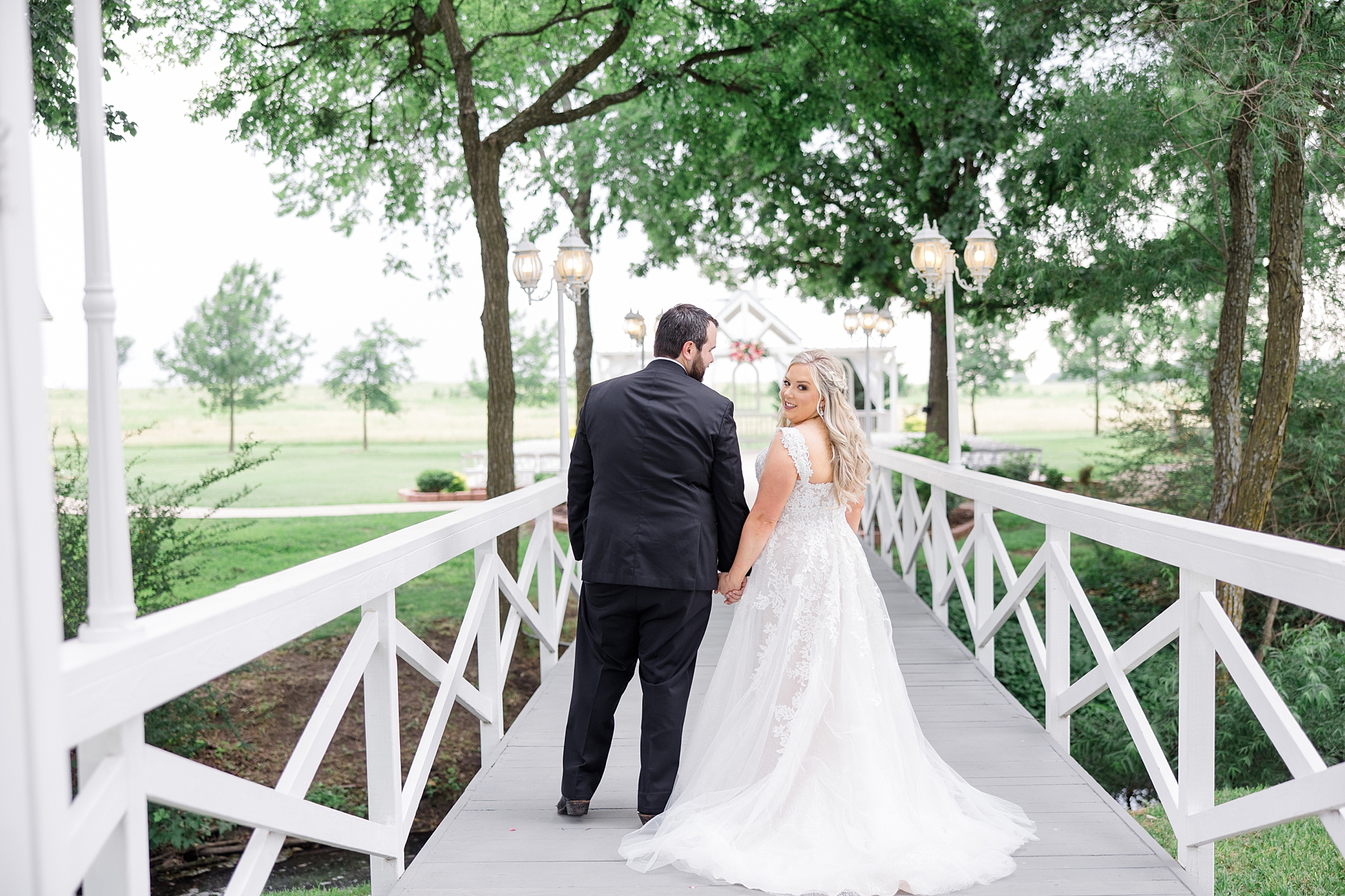 groom looks down at bride during portraits on white bridge at Willow Creek