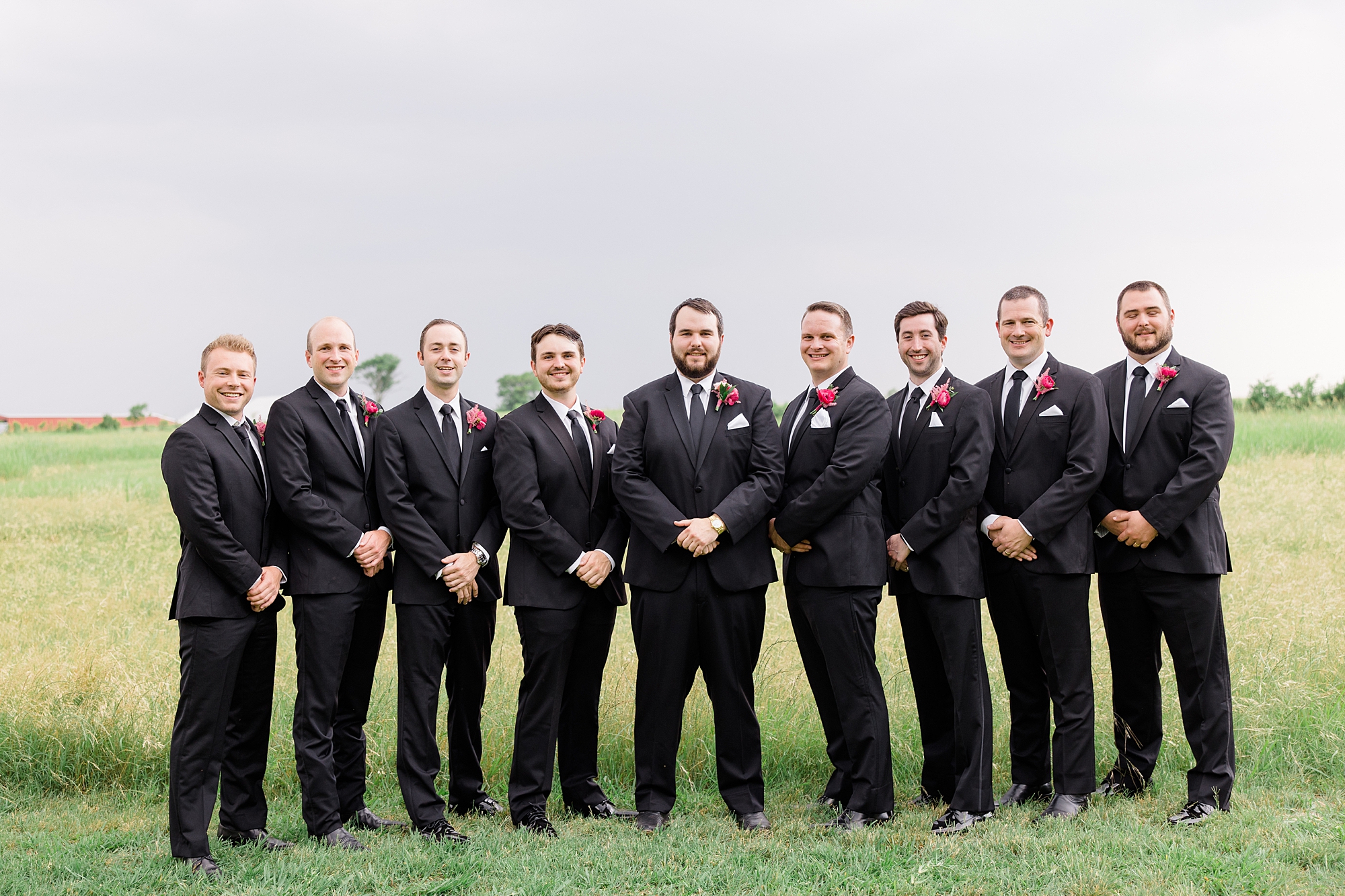 groom stands with groomsmen in black suits at Willow Creek