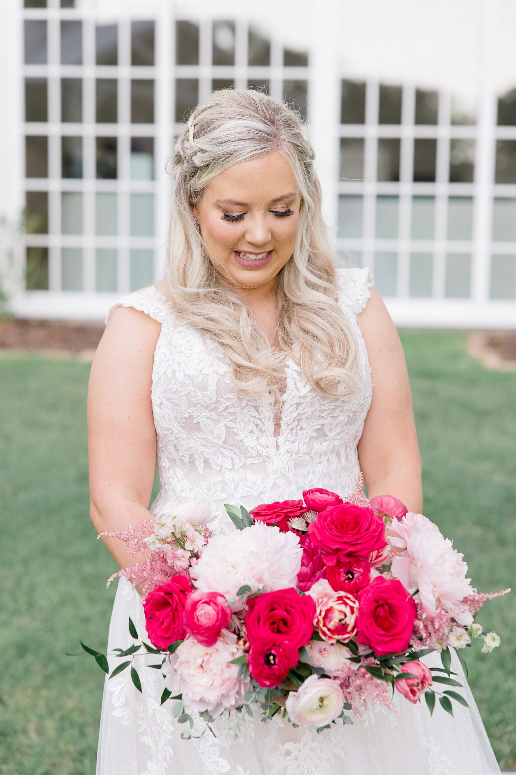 bride looks down at pink and red bouquet at Willow Creek