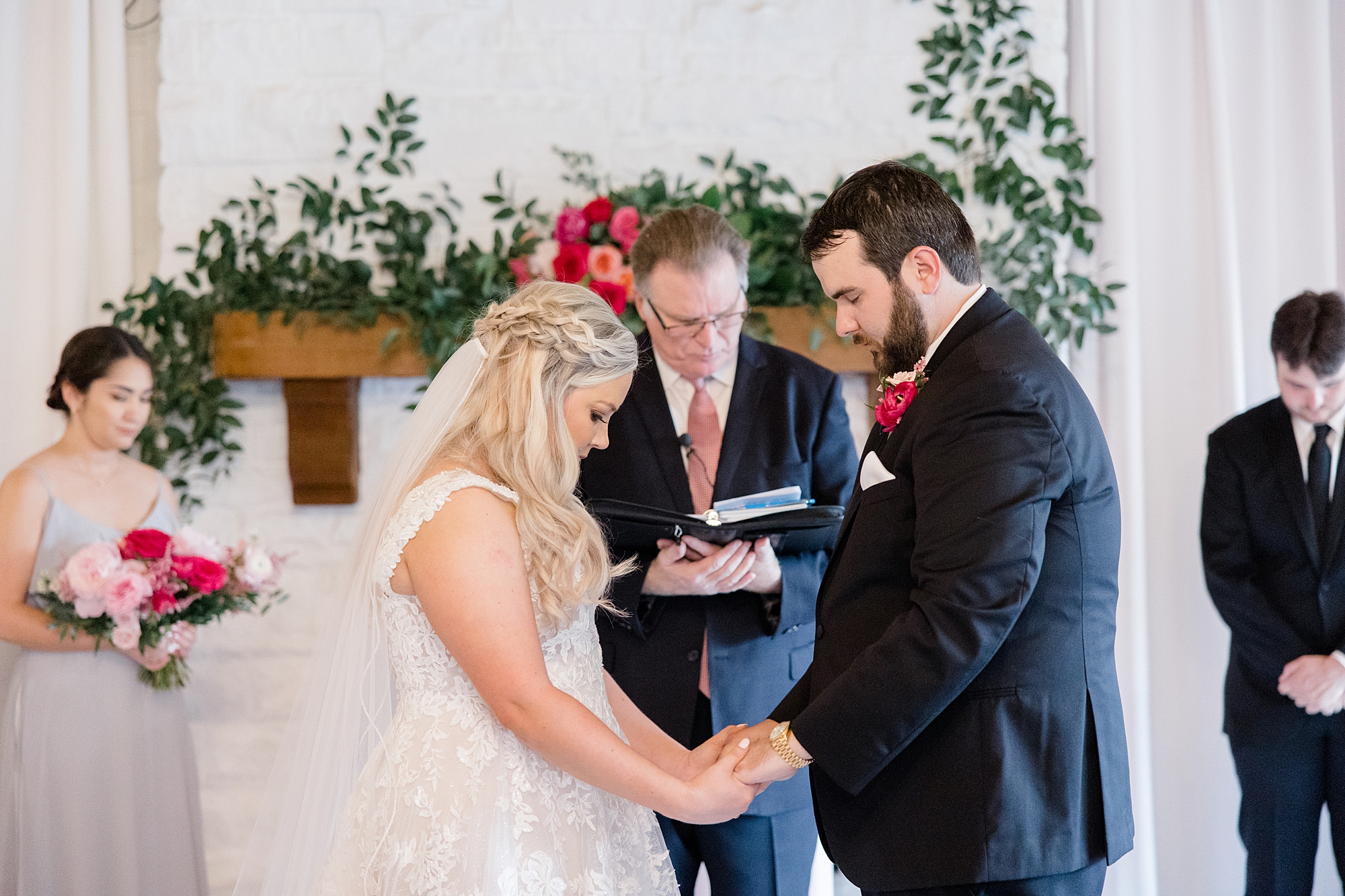 newlyweds hold hands and bow head during Willow Creek wedding ceremony 