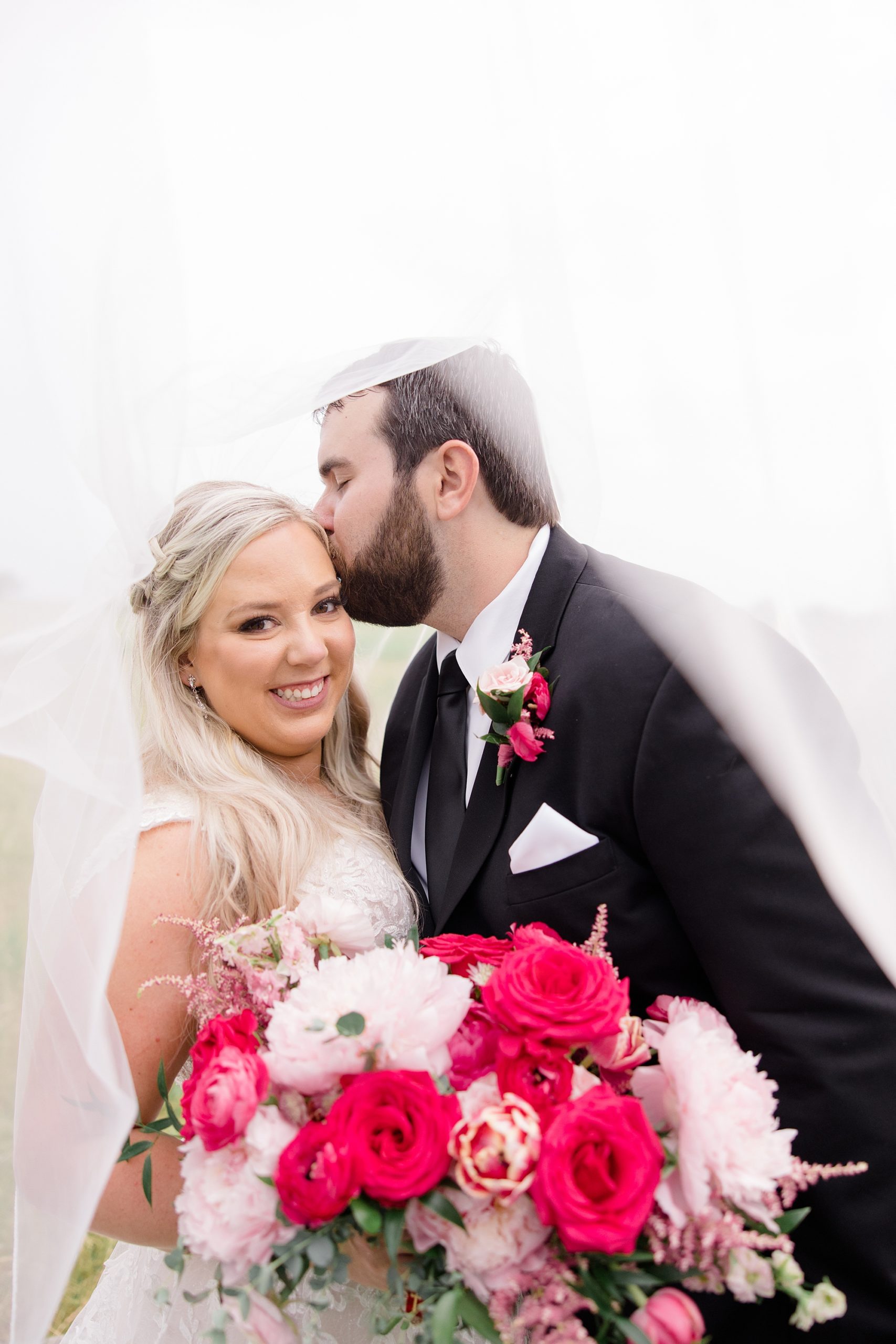groom leans to kiss bride's forehead during TX wedding photos