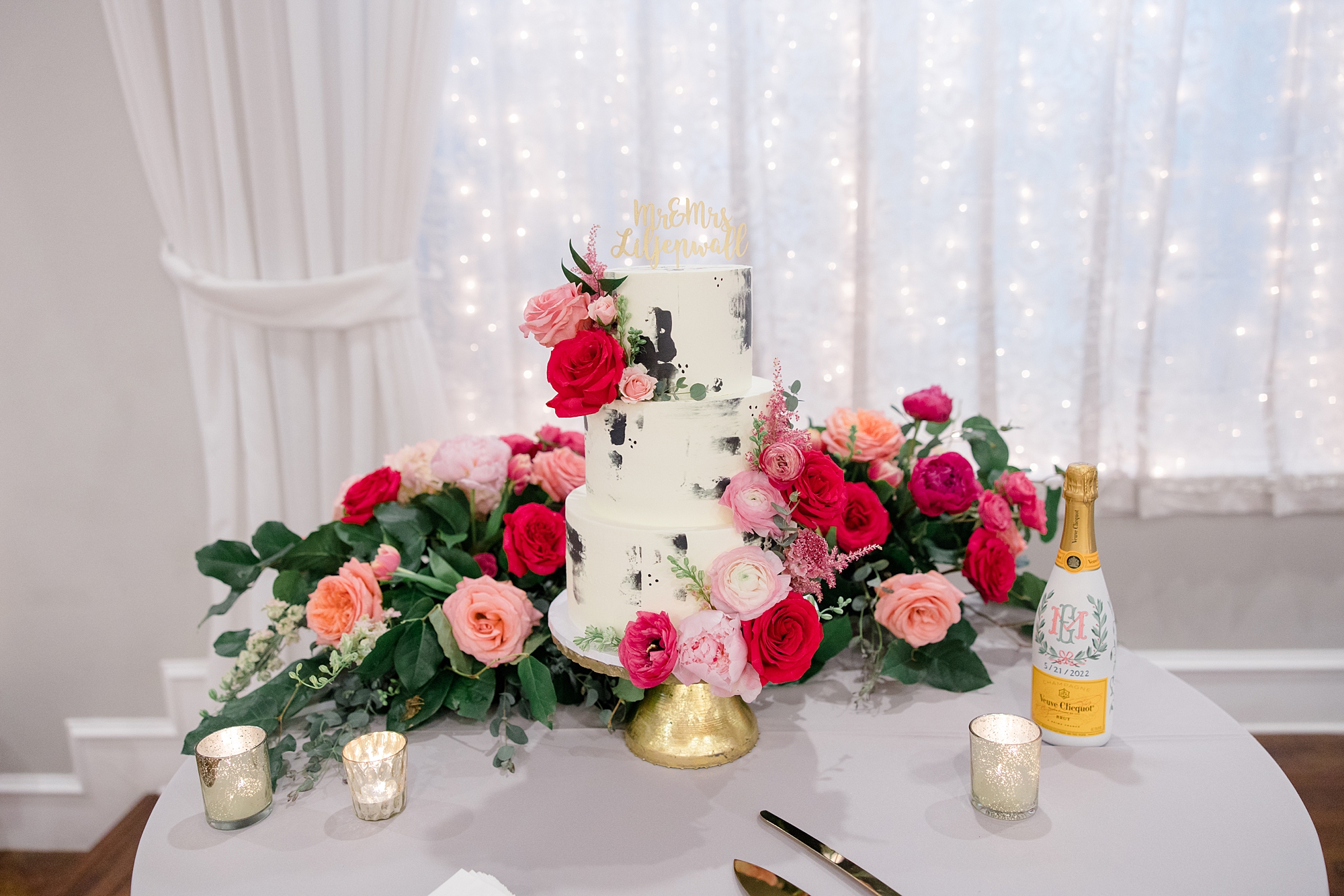 cake display with pink flowers and gold votive candles