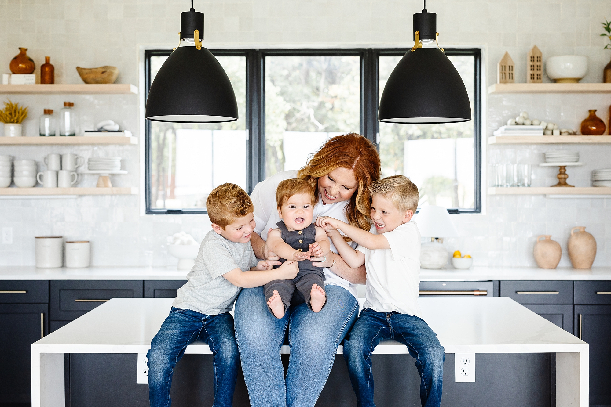 mom sits on kitchen counter playing with three sons