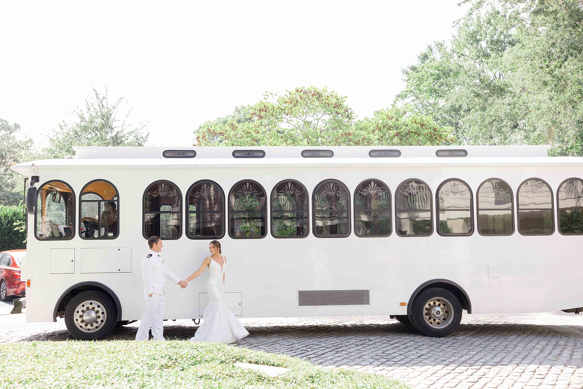 bride and groom hold hands by white trolley in Charleston SC