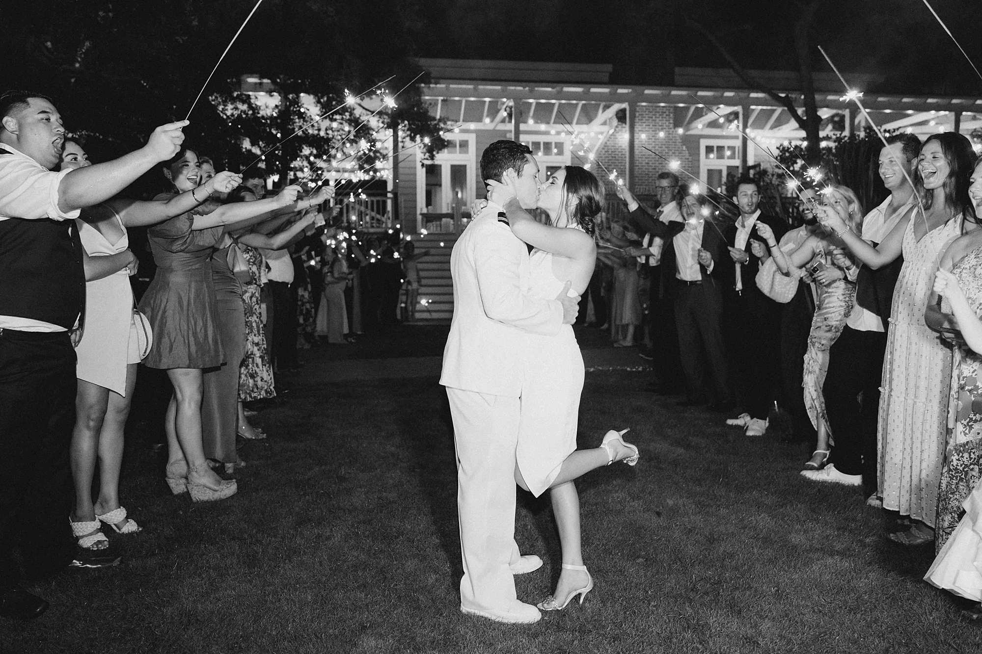bride and groom kiss during sparkler exit and bride pops heel