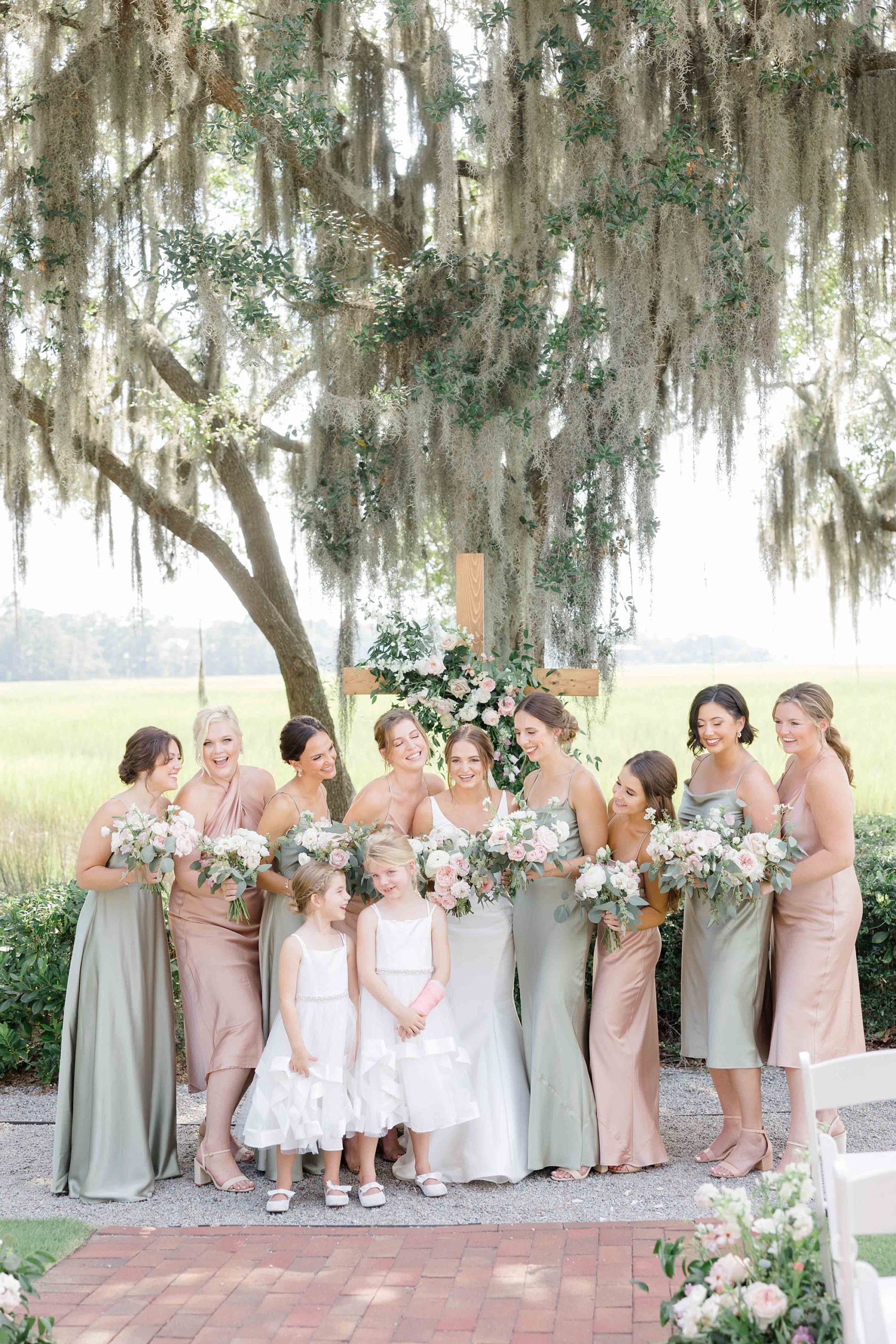 bride stands with bridesmaids in sage green and pale pink