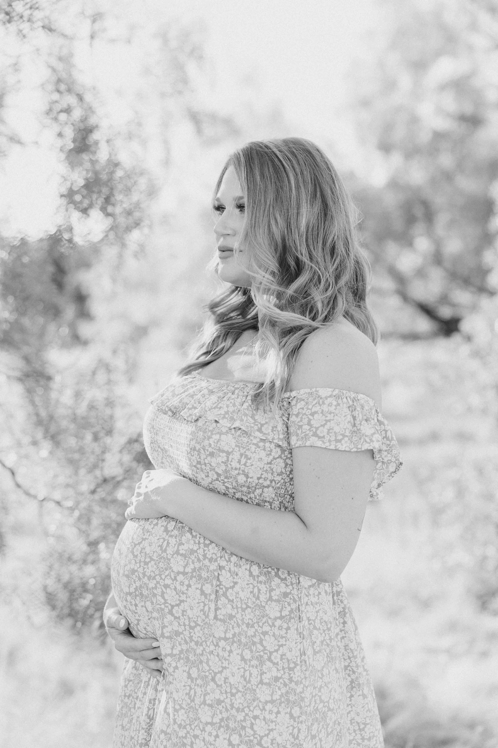 mother looks out in field while holding baby bump during summertime Murrell Park maternity session