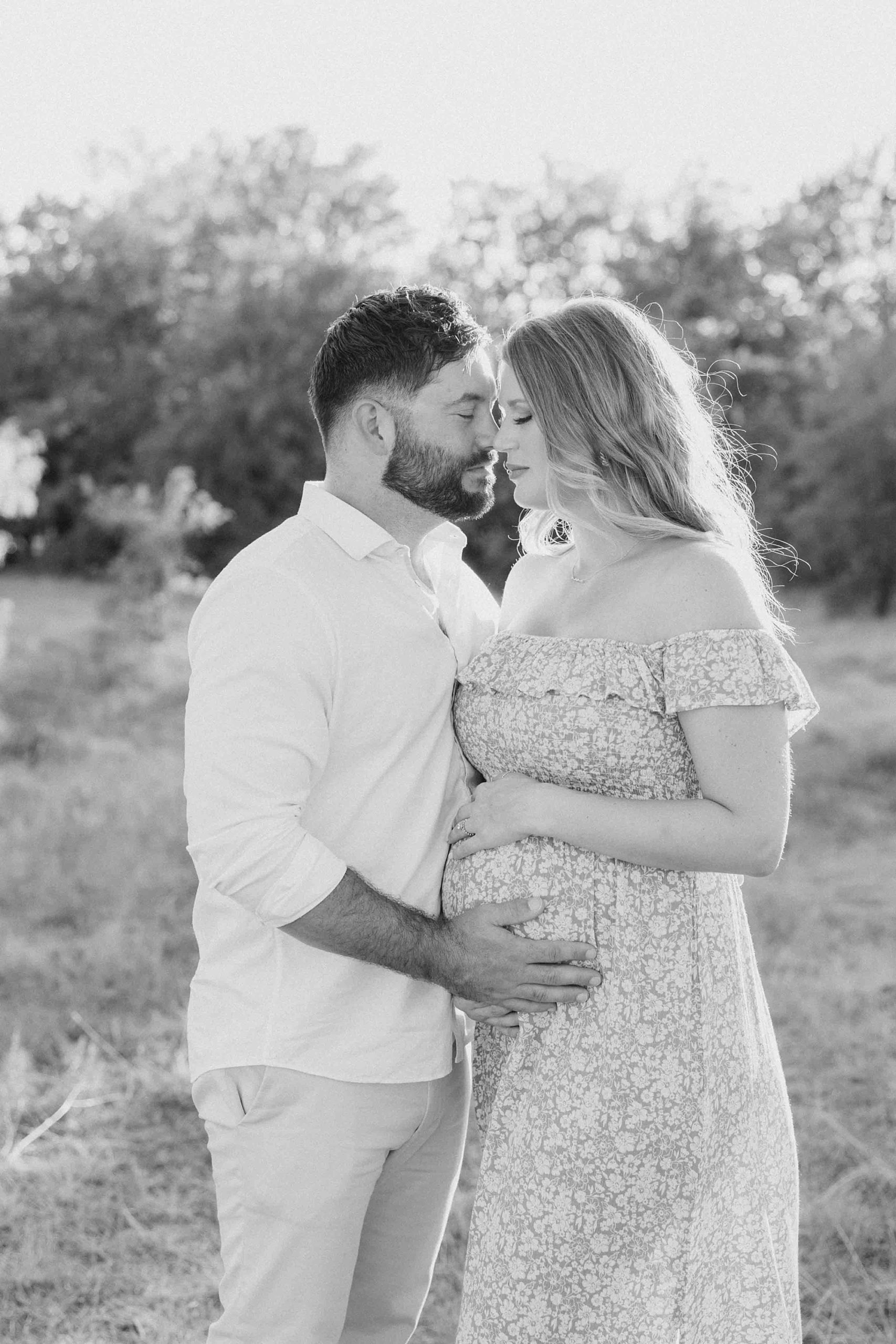 couple leans foreheads together during summertime maternity photos