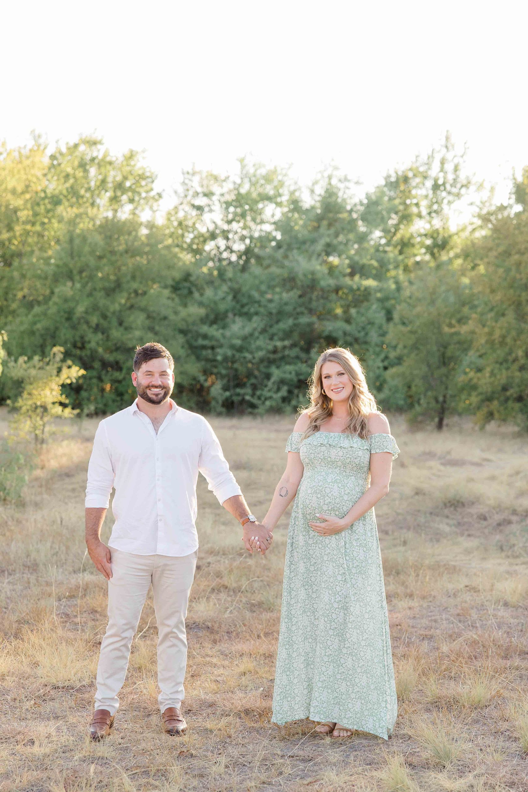 couple holds hands standing in field at sunset during Murrell Park maternity session