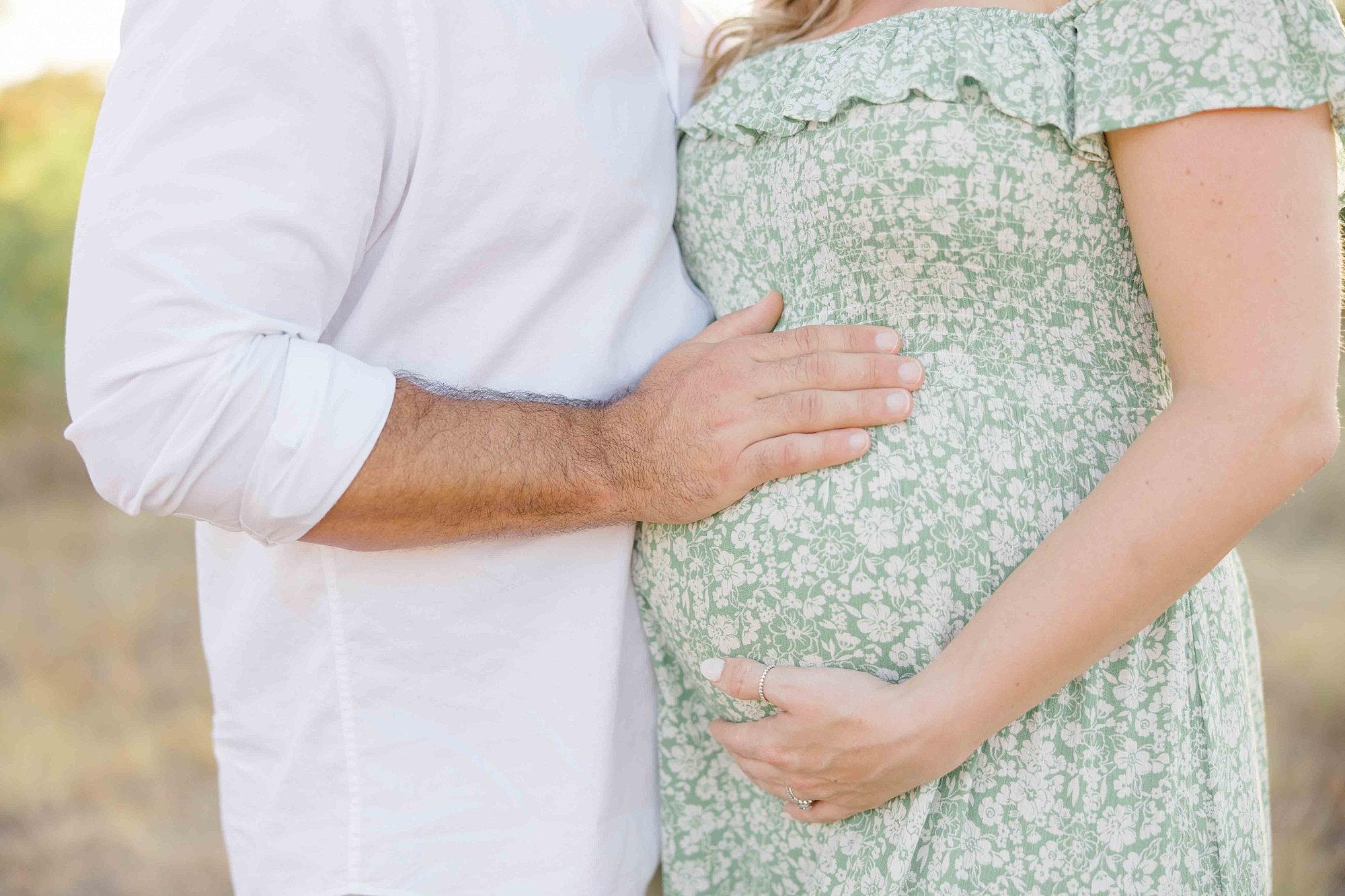 woman and husband hold baby bump during summer maternity photos 