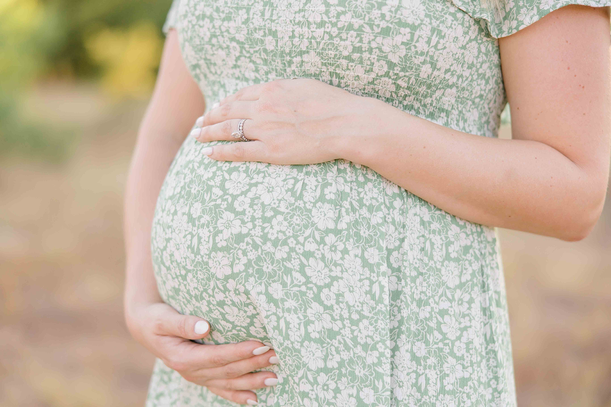 woman in green dress holds baby bump during Murrell Park maternity session