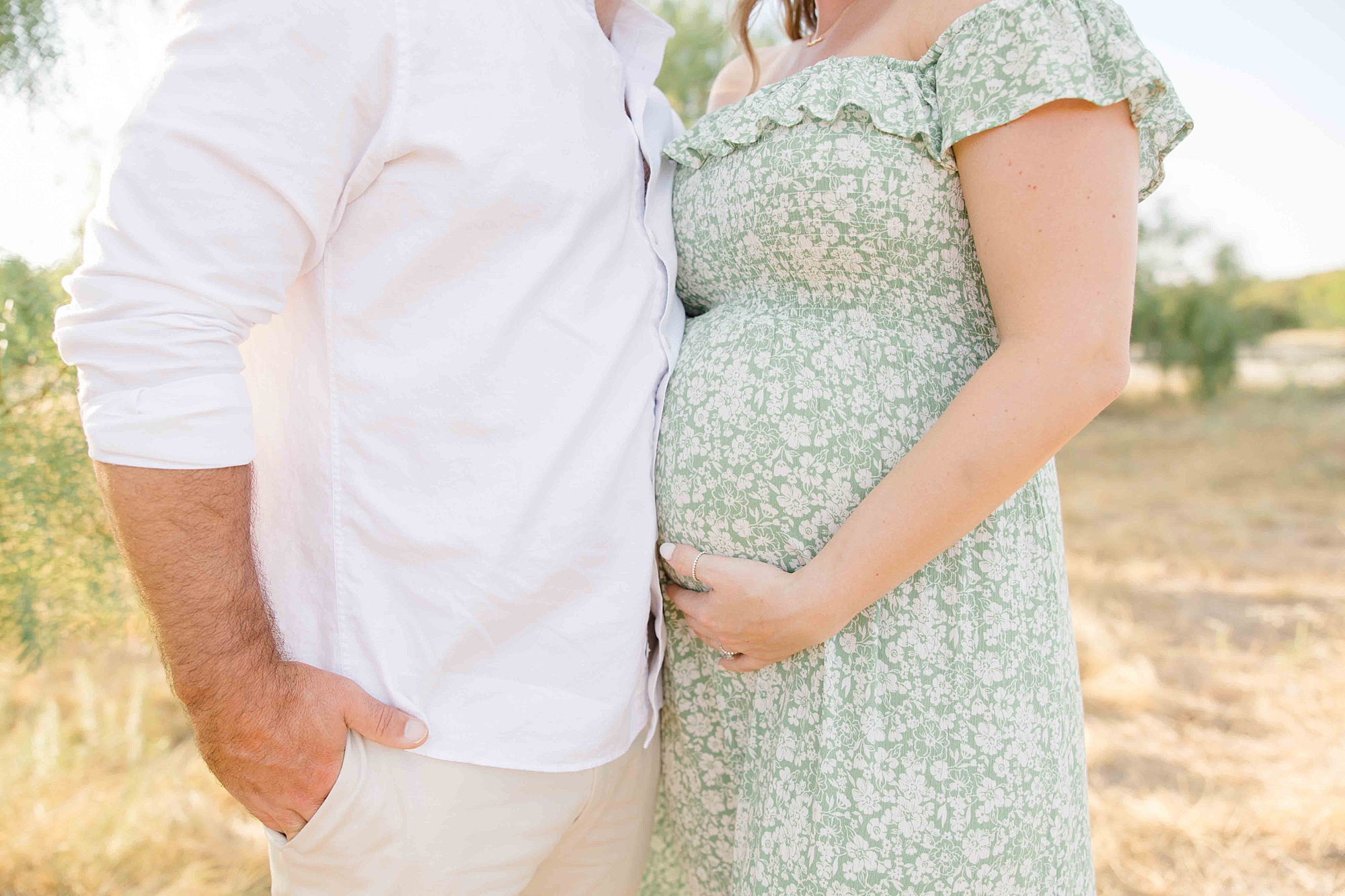 mother holds belly in green dress during summer Murrell Park maternity session