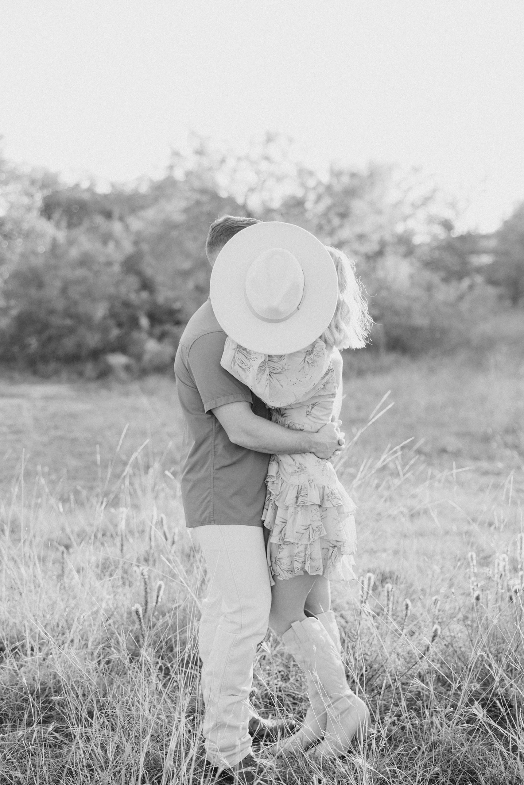 bride and groom kiss behind hat in field at Murrell Park