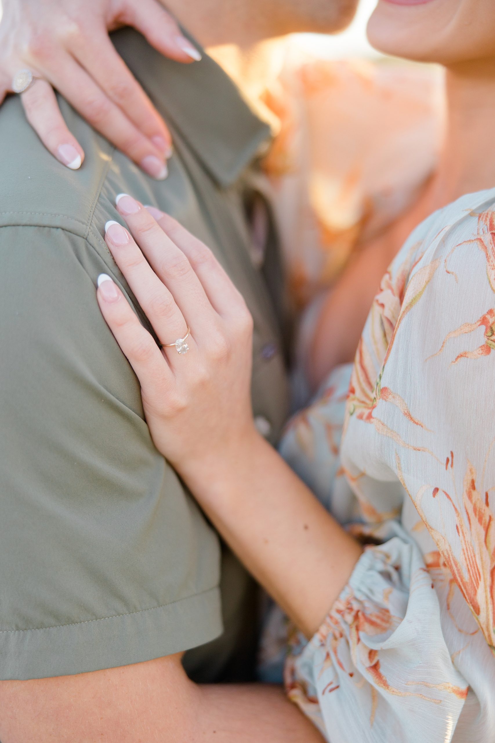 woman puts hand on man's chest in green shirt showing off ring 