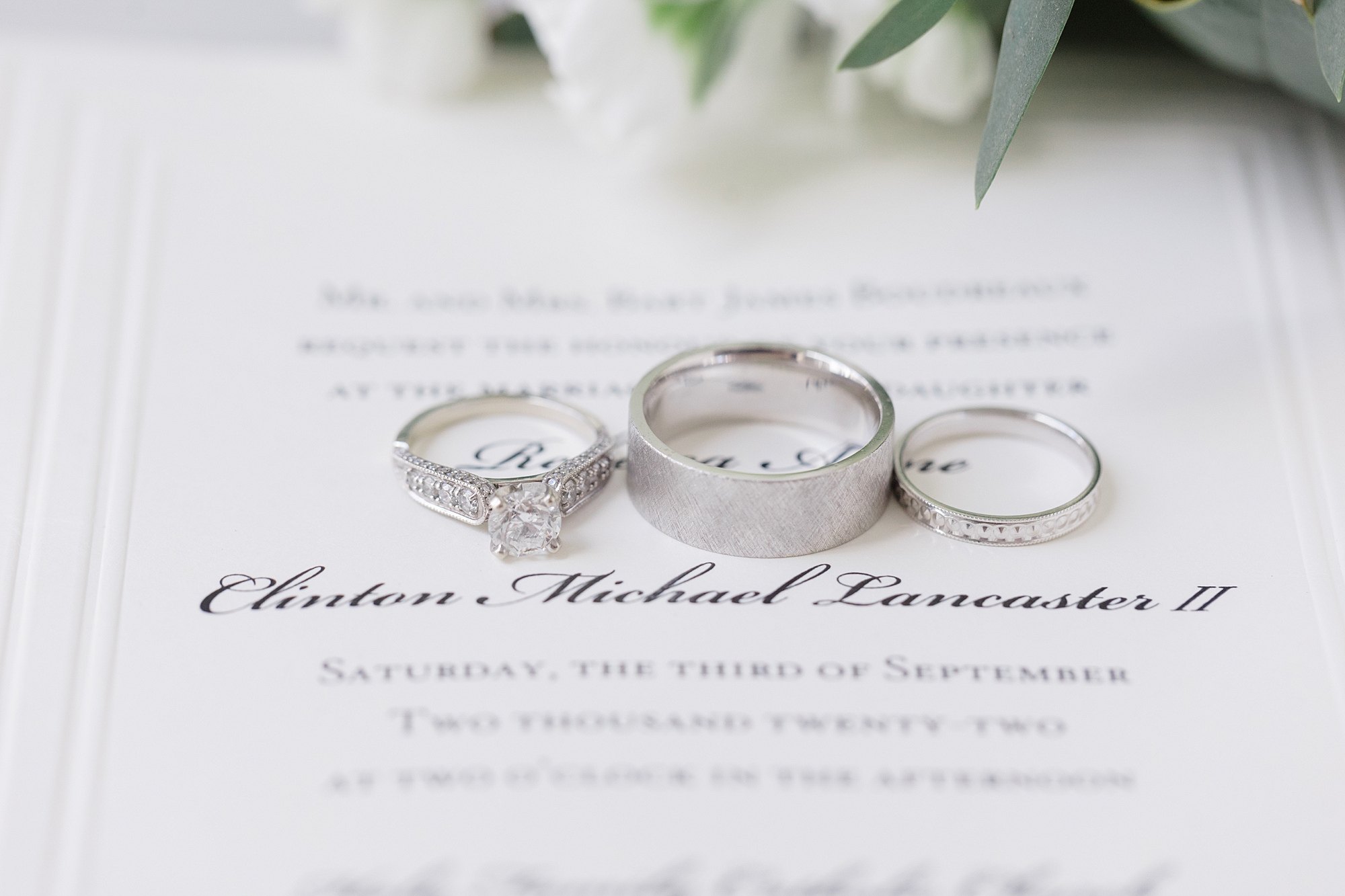 three silver wedding bands rest on classic invitation suite 