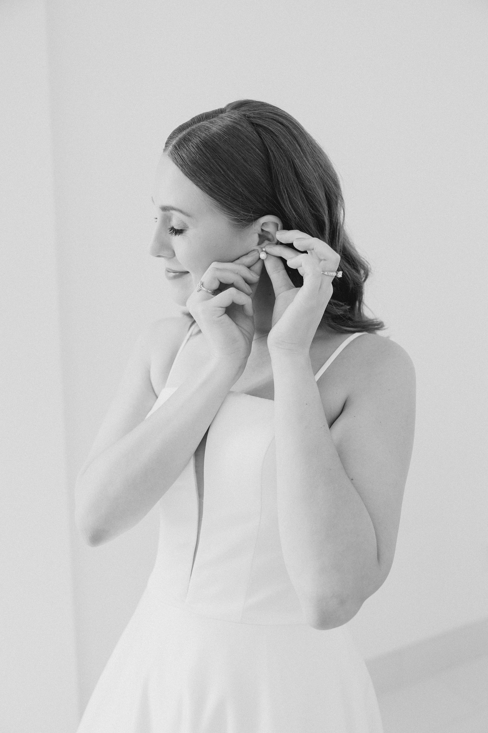 black and white portrait of bride adjusting earring
