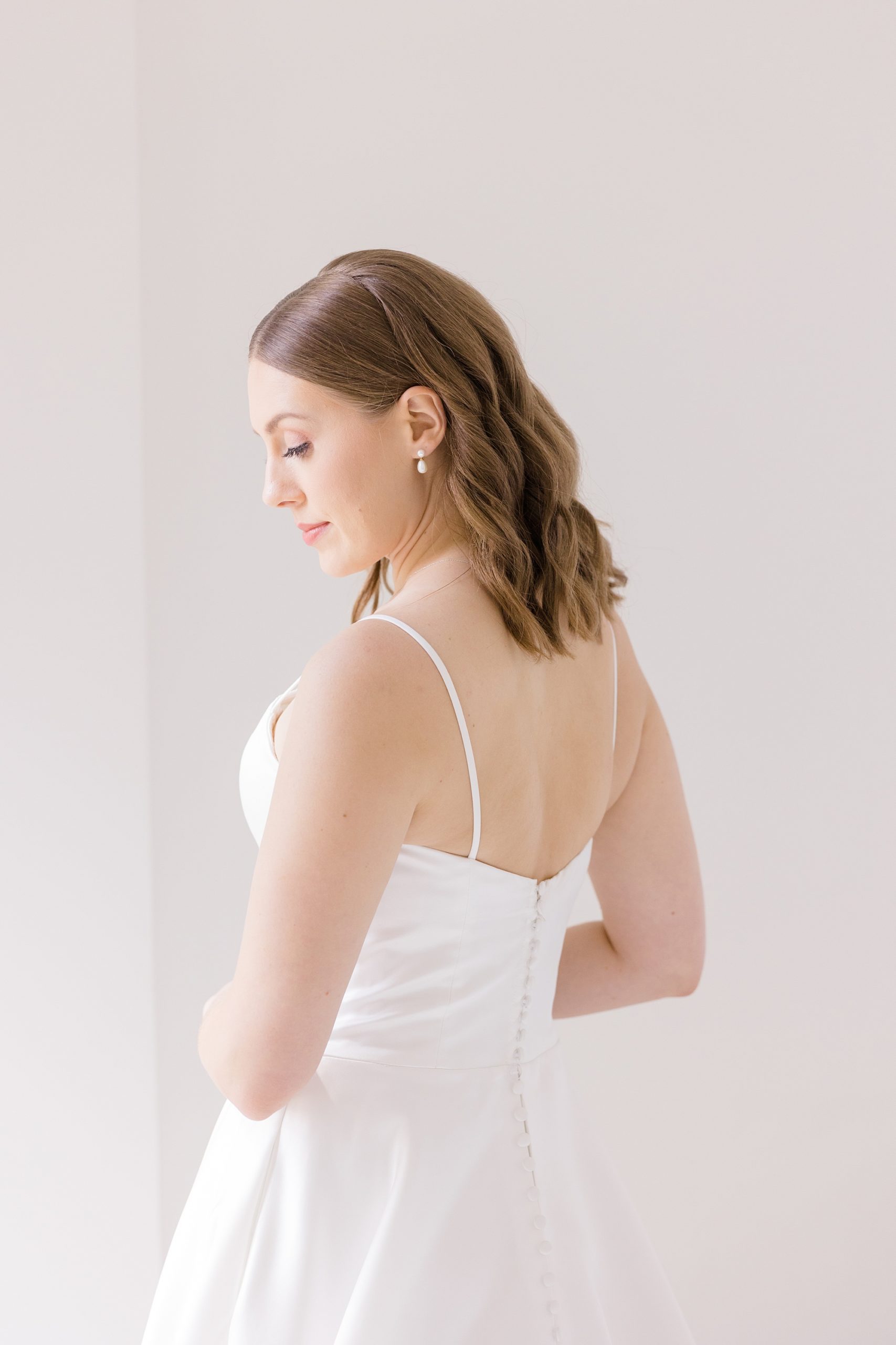 bride looks down showing off back of wedding gown 
