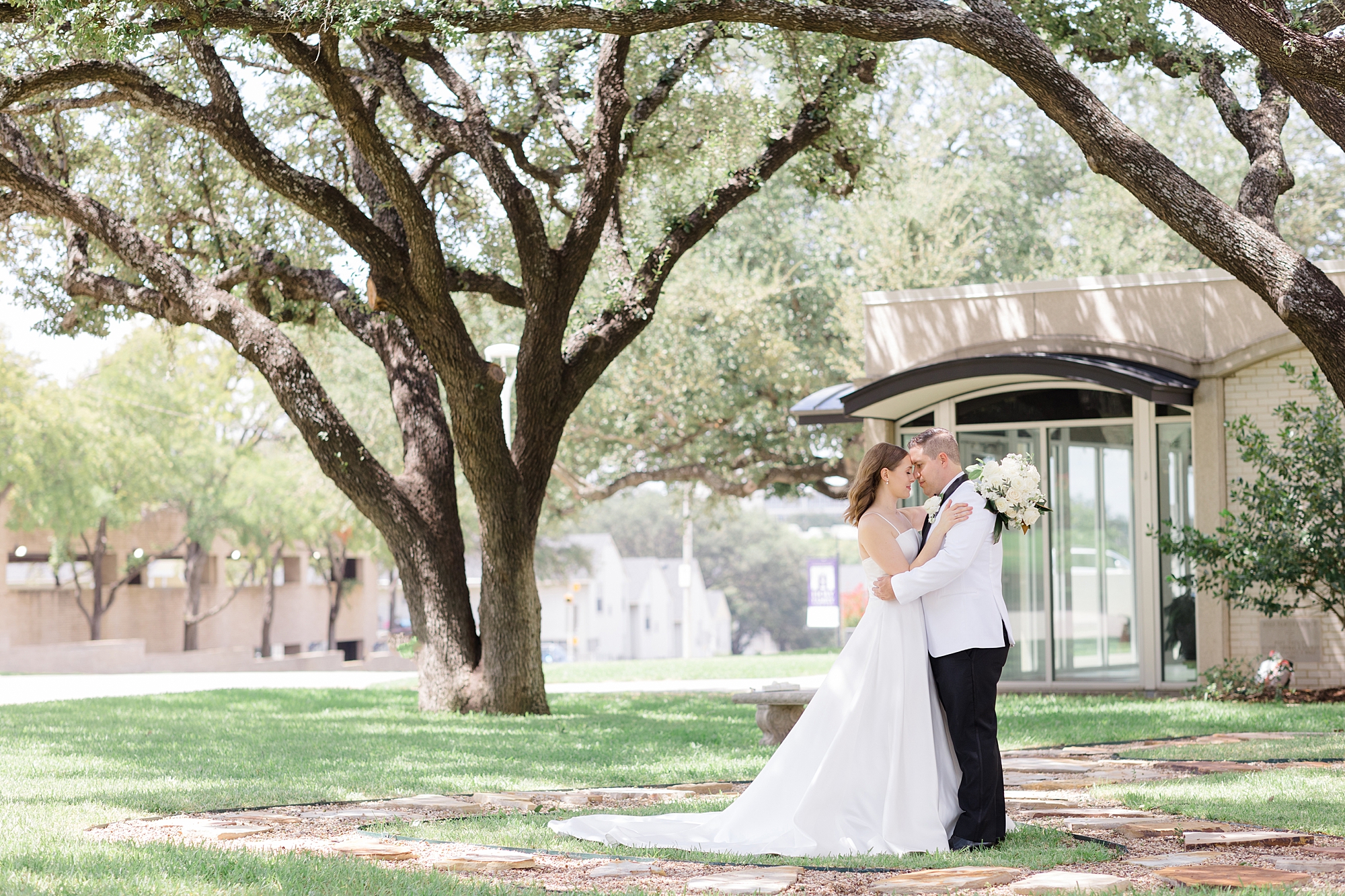 bride and groom hug on lawn of Fort Worth TX church 