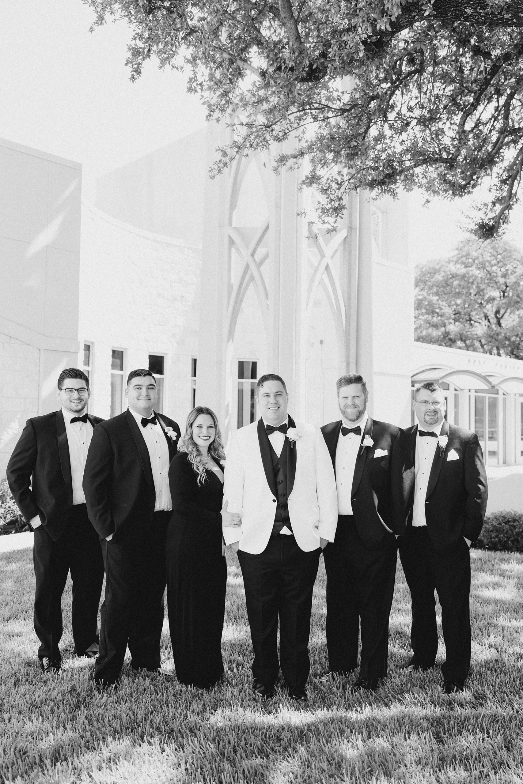groom stands with groomsmen on lawn at church in Fort Worth TX