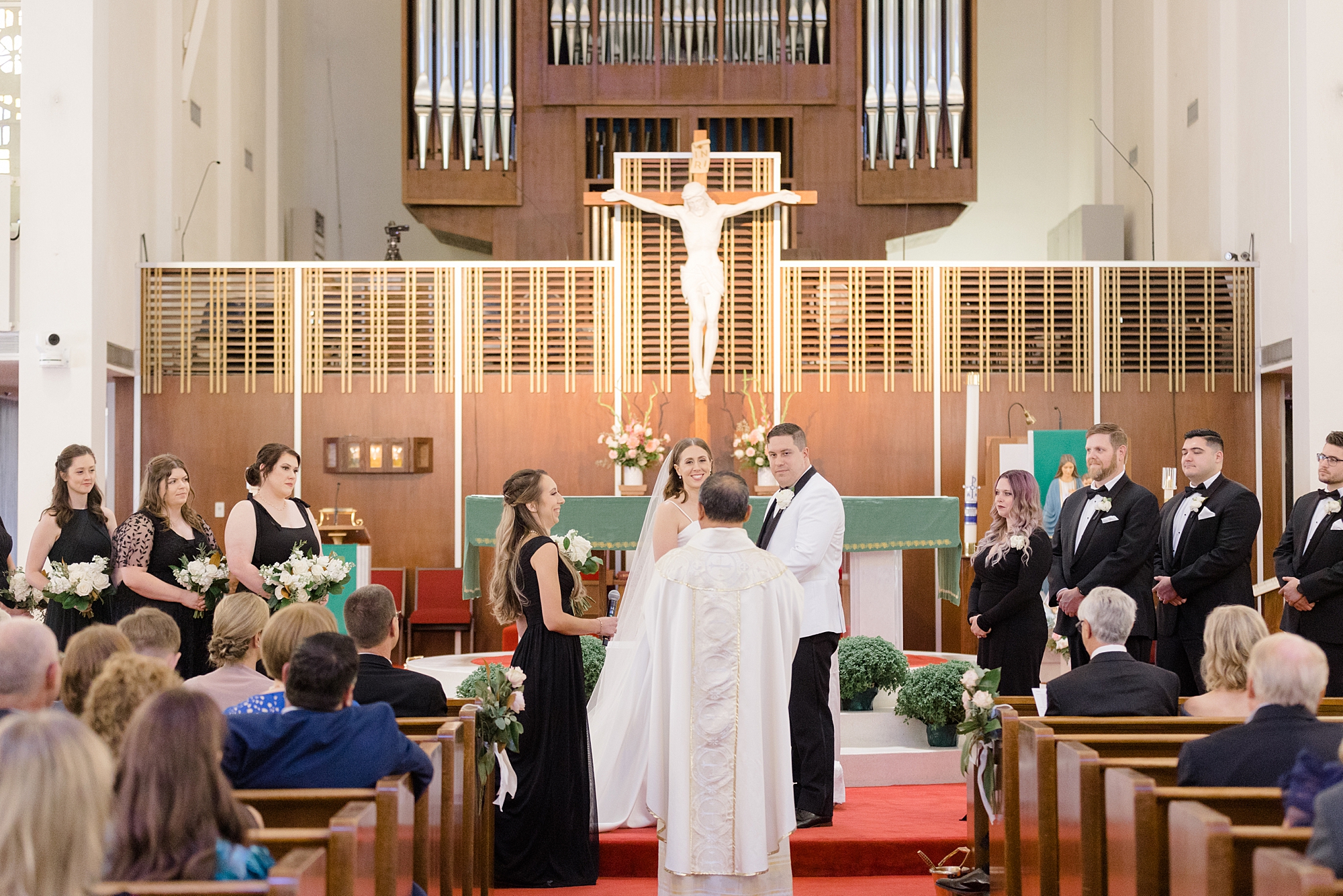 father officiates ceremony in front of couple at alter in Holy Family Catholic Church