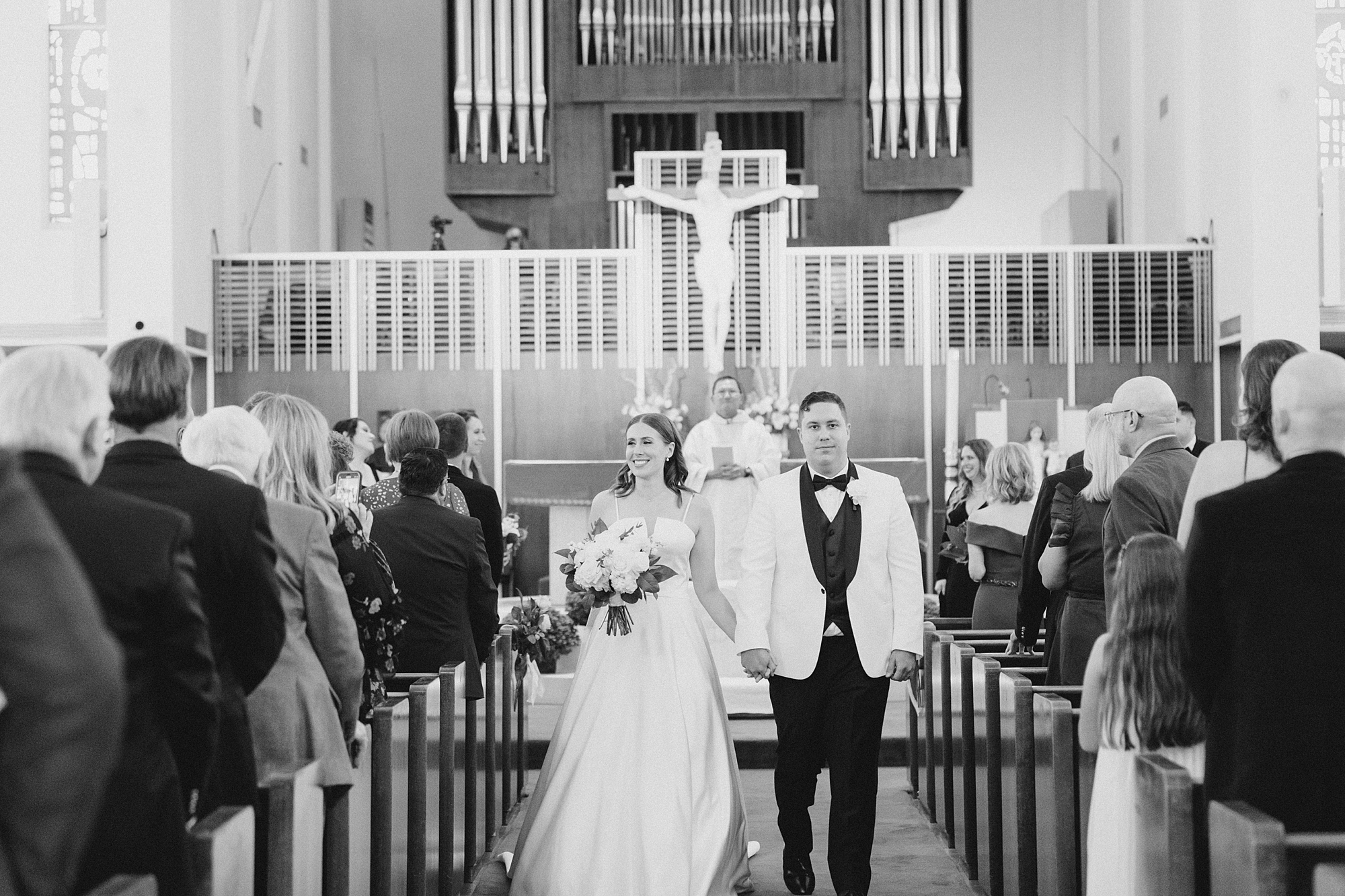 couple walks up aisle after ceremony in Holy Family Catholic Church