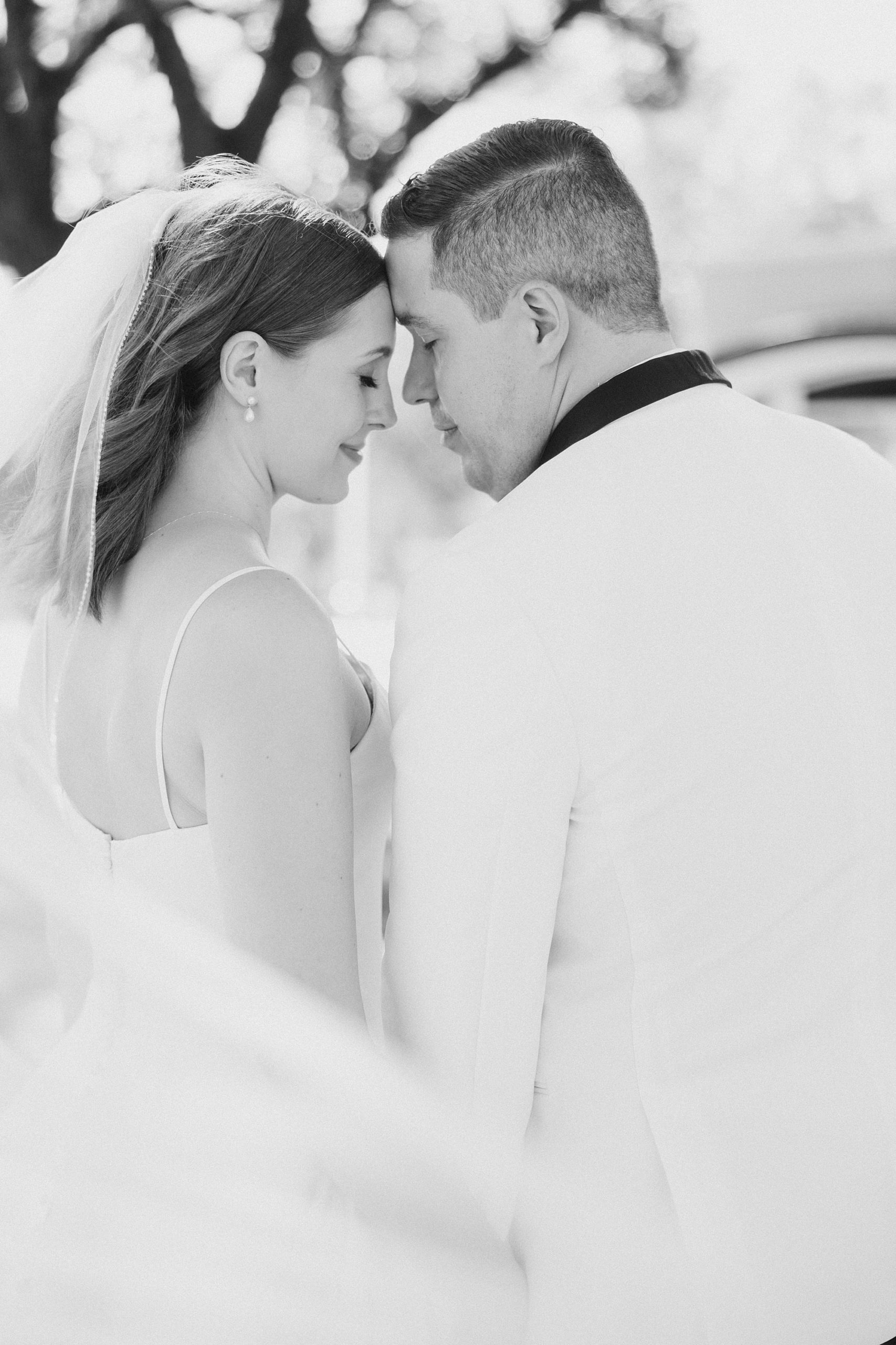 black and white portrait of bride and groom leaning heads together 
