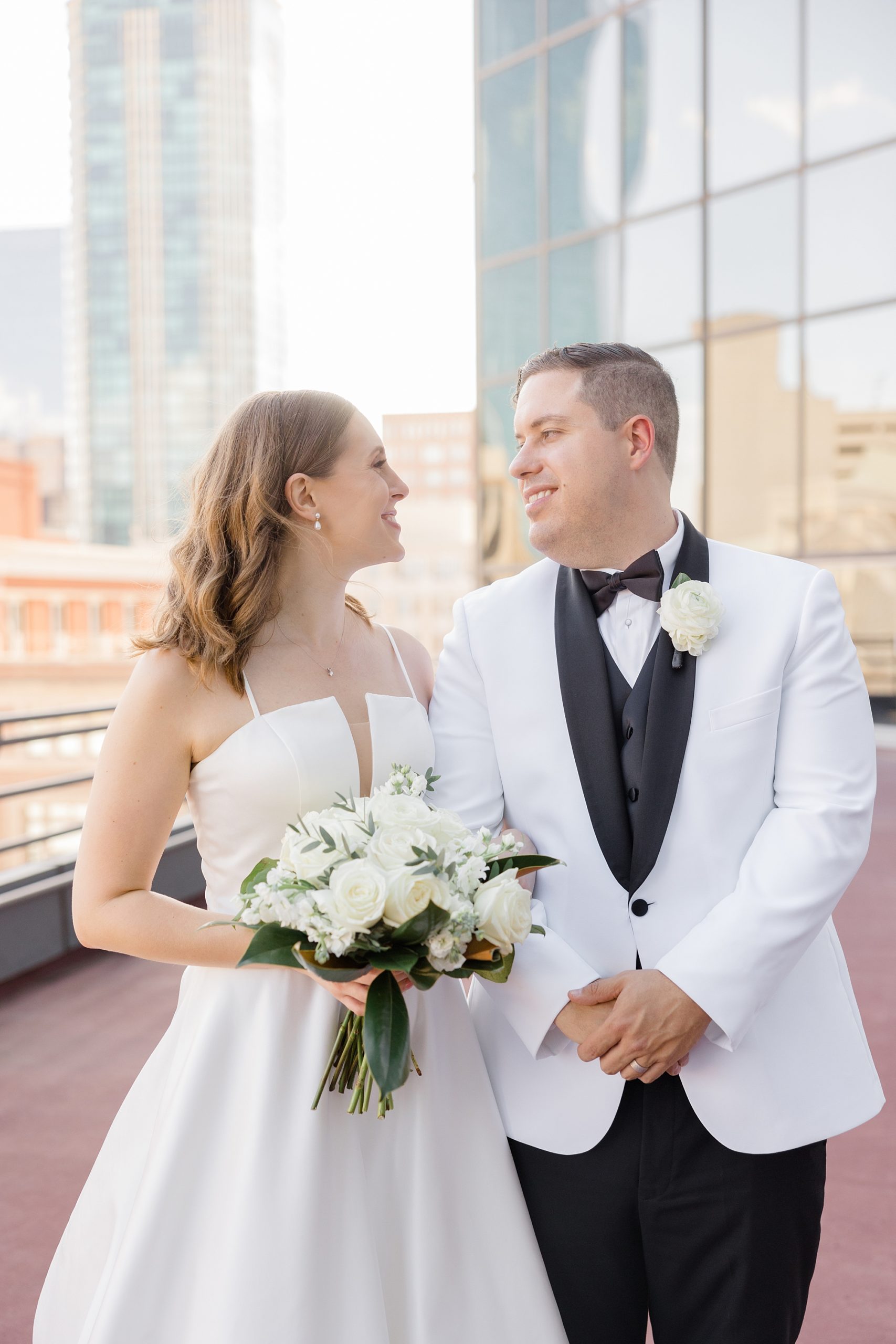 bride smiles at groom in white suit jacket outside Fort Worth City Club