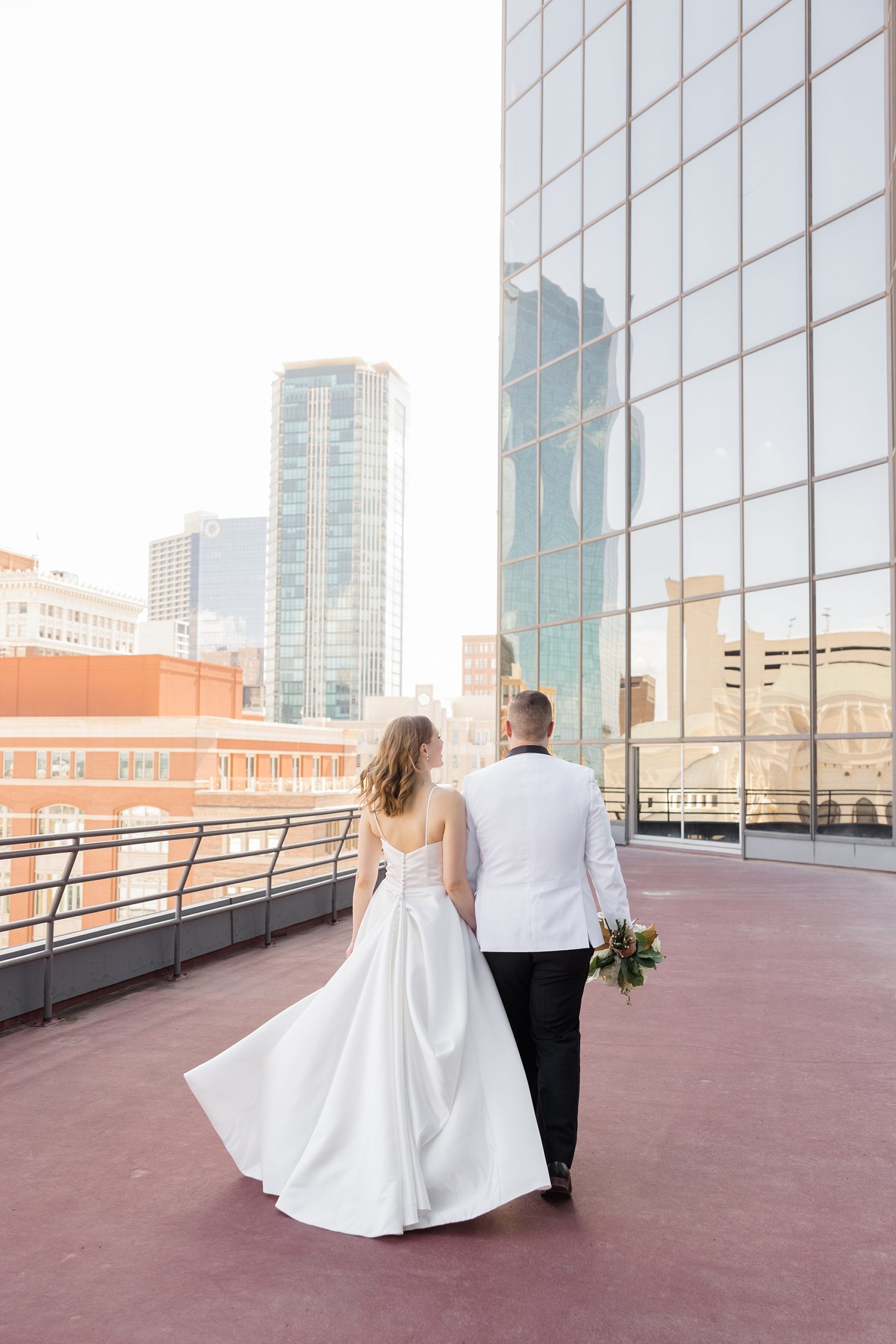 newlyweds hold hands walking on balcony of Fort Worth City Club