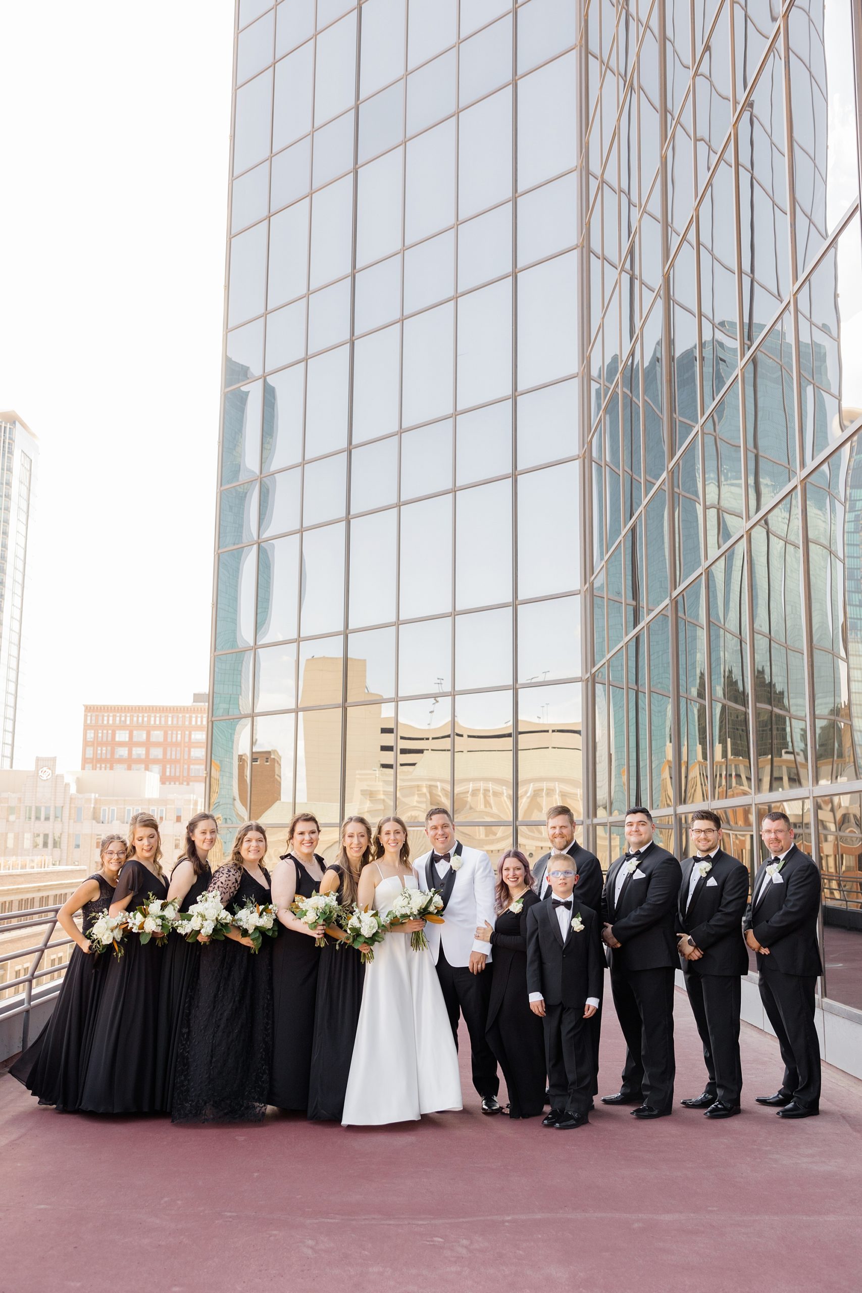 newlyweds pose with wedding party in black attire at Fort Worth City Club