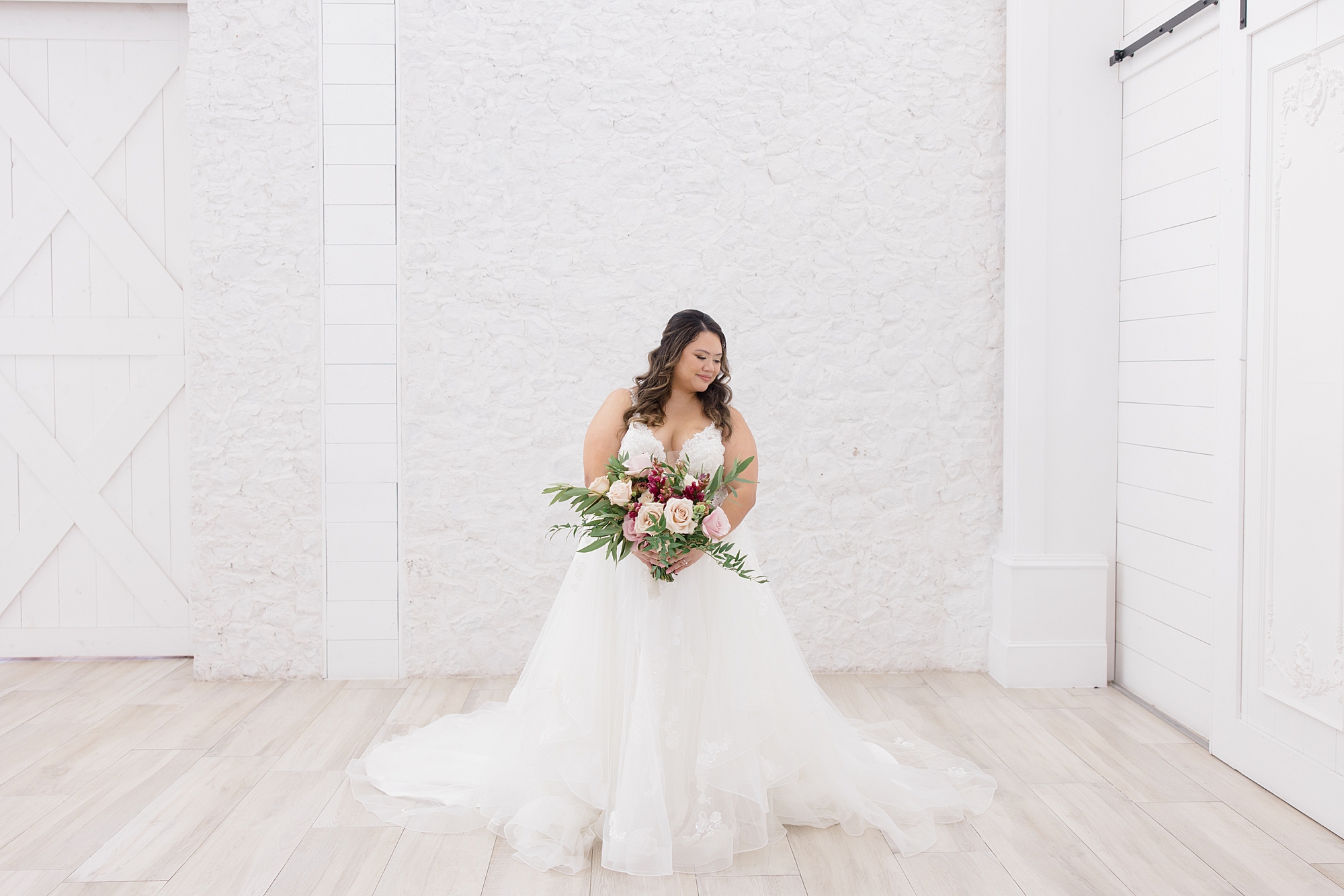 bride stands in front of white wall at The Nest at Ruth Farms