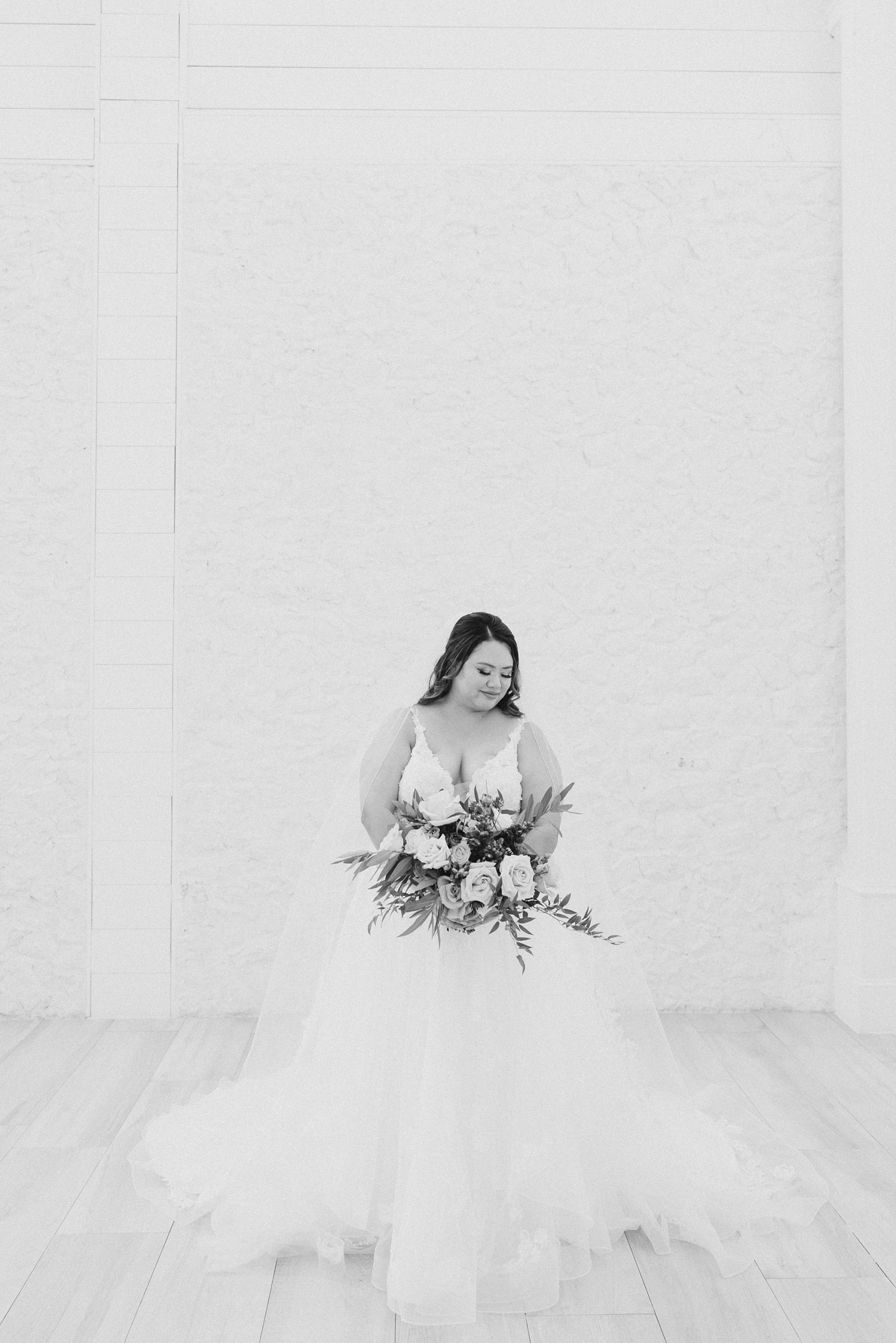 black and white portrait of bride looking over shoulder down at floor 