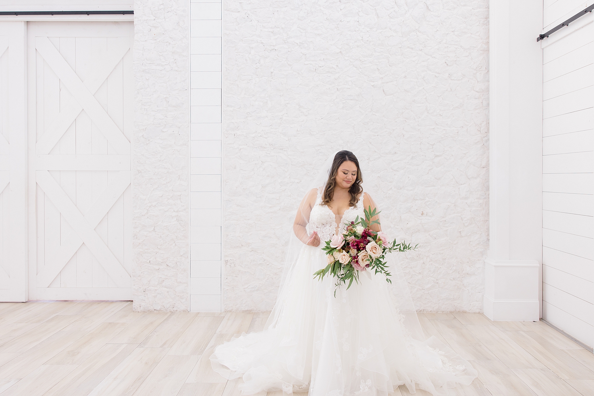 bride poses by white brick wall inside The Nest at Ruth Farms