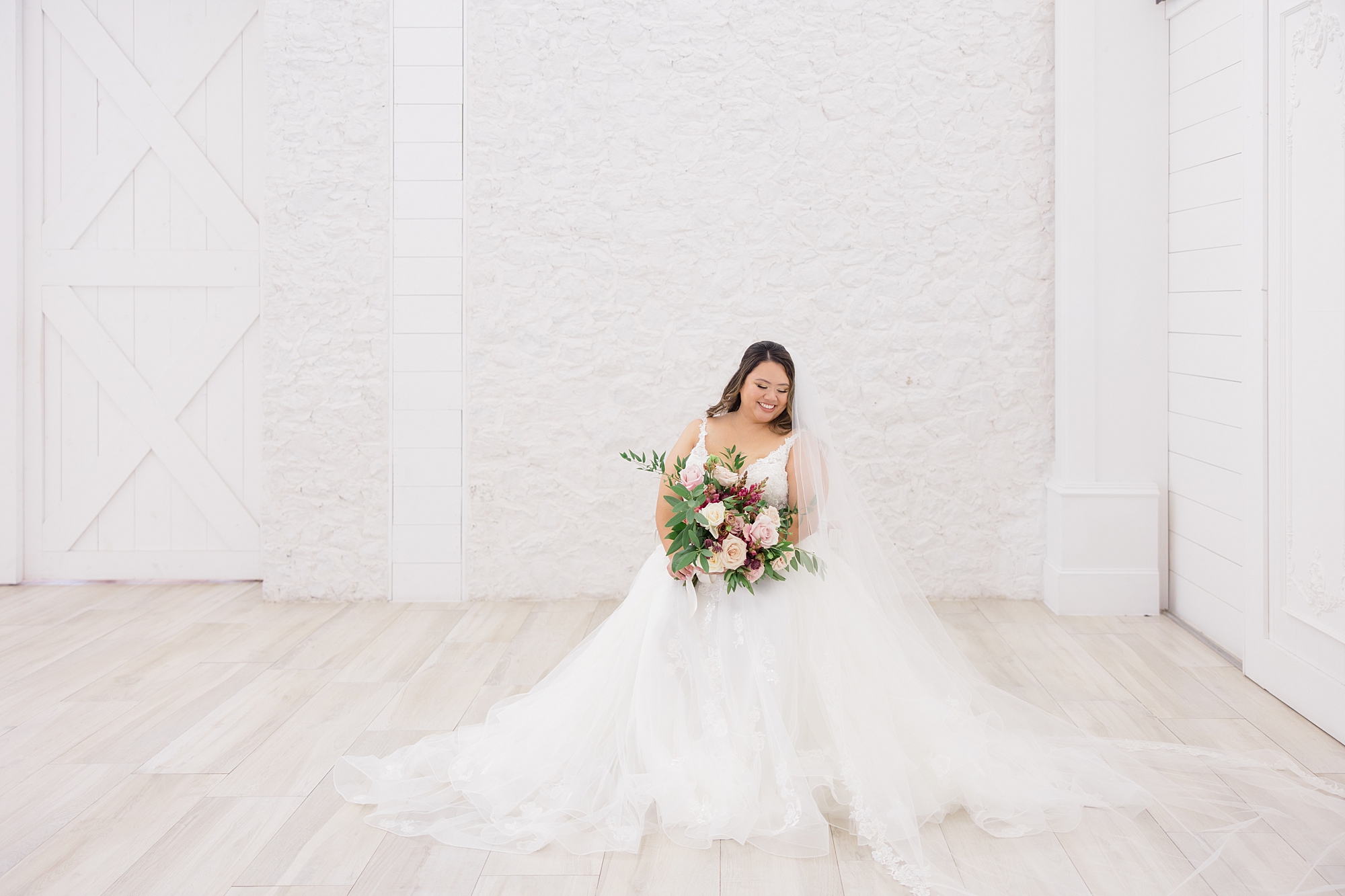 bride poses in wedding dress with full skirt by brick wall at The Nest at Ruth Farms