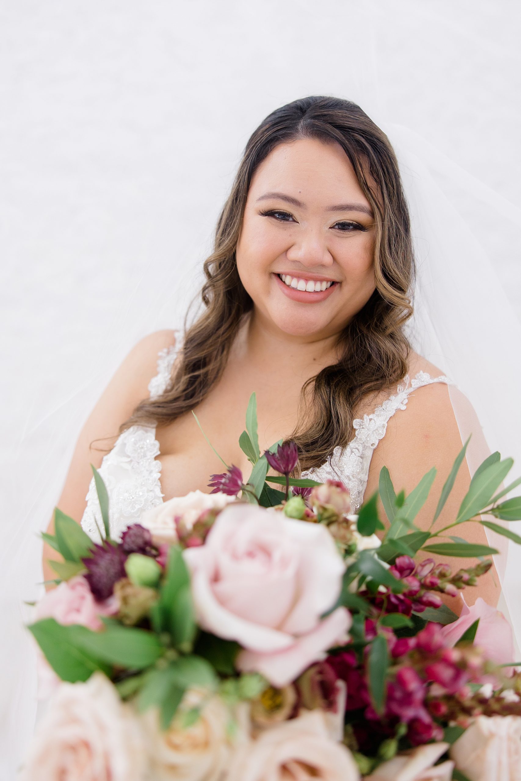 bride smiles holding bouquet of pink roses 