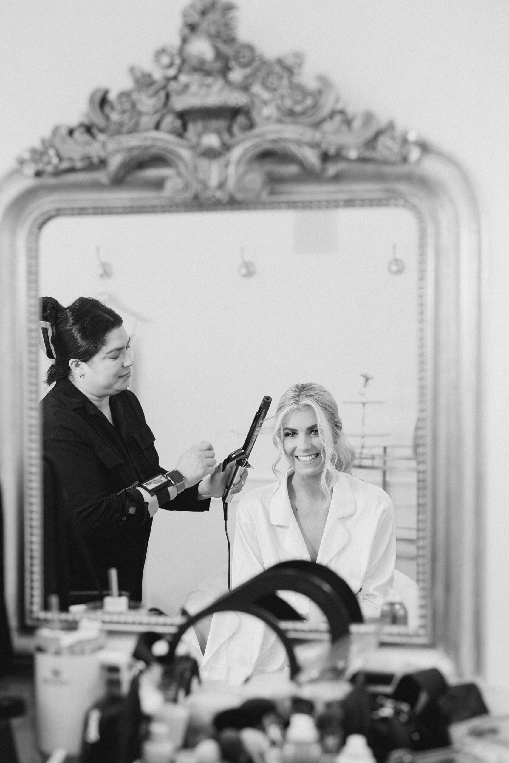 woman does bride's hair in reflection of mirror 