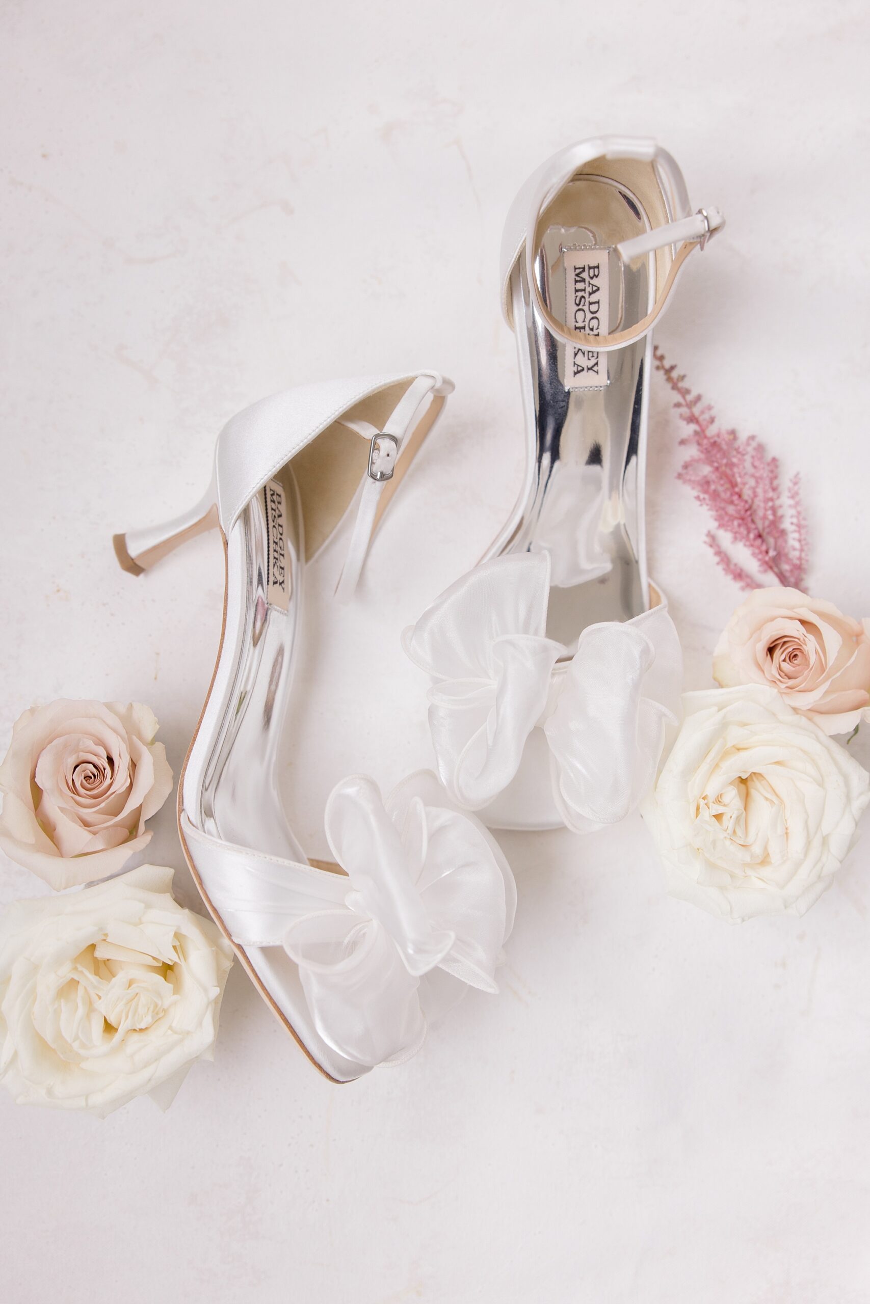 bride's wedding shoes lay next to ivory and pale pink roses 