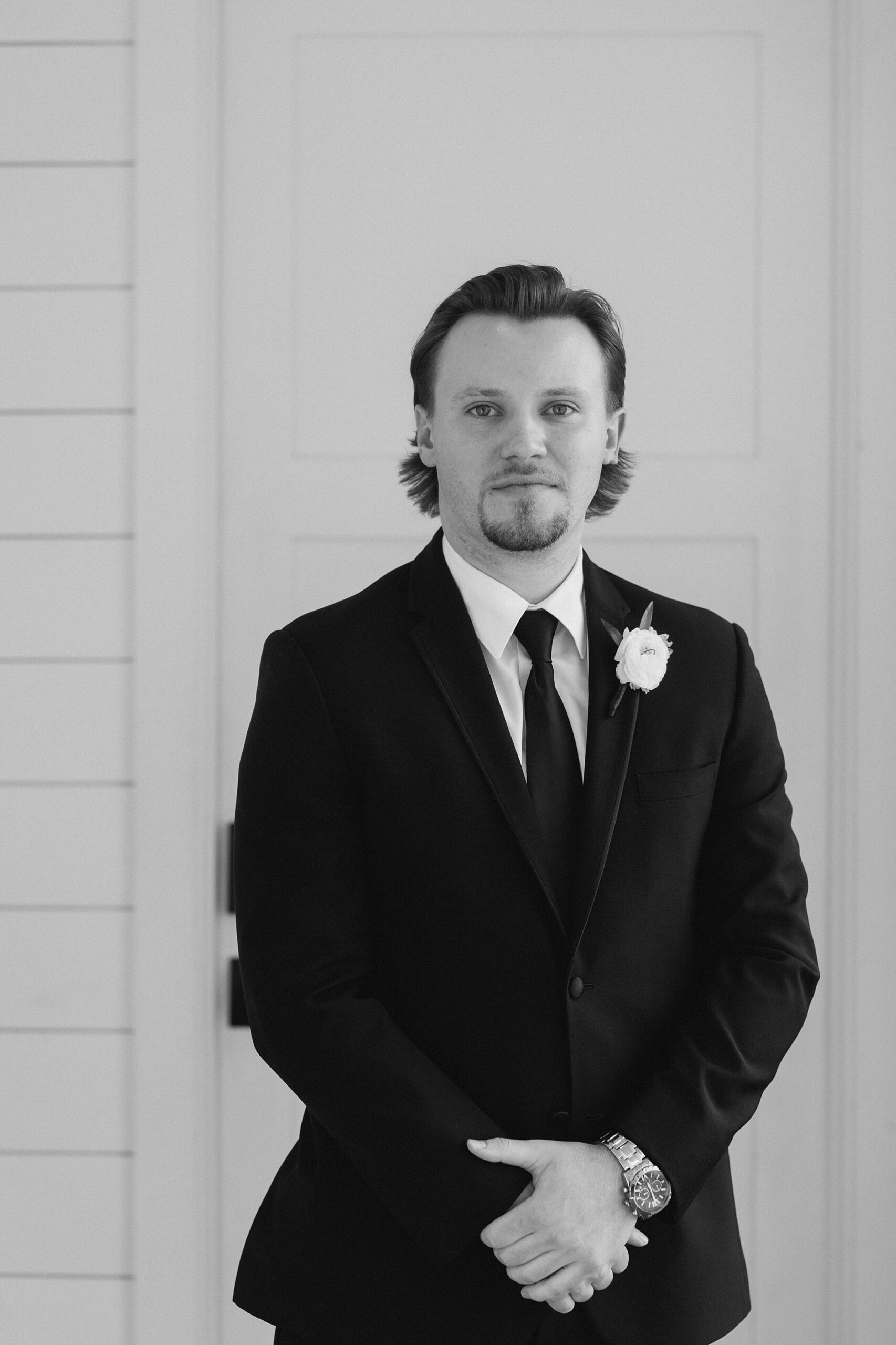 black and white portrait of groom in black suit with white boutonnière 