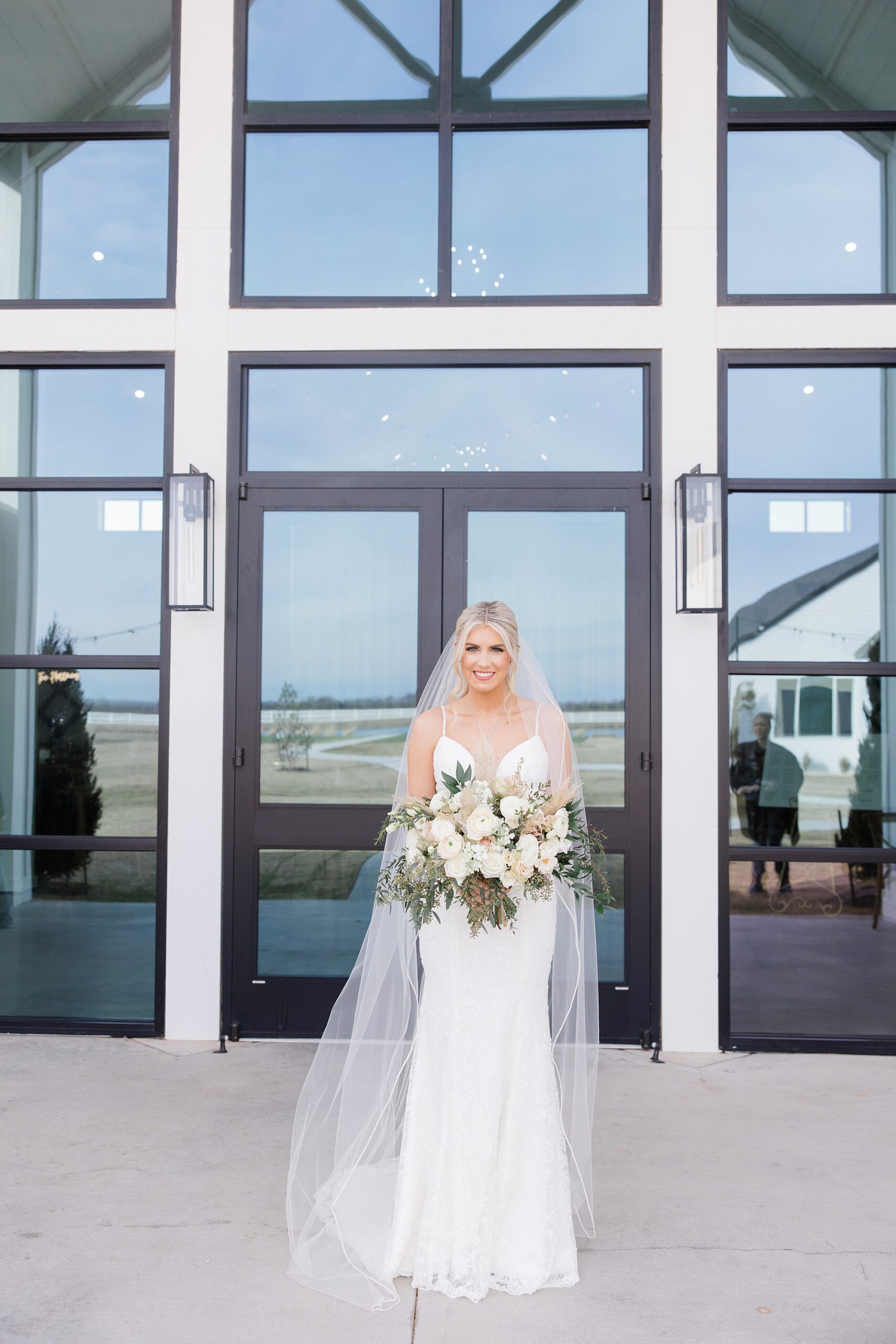 bride holds bouquet of pink and ivory flowers outside windows at The Gardenia