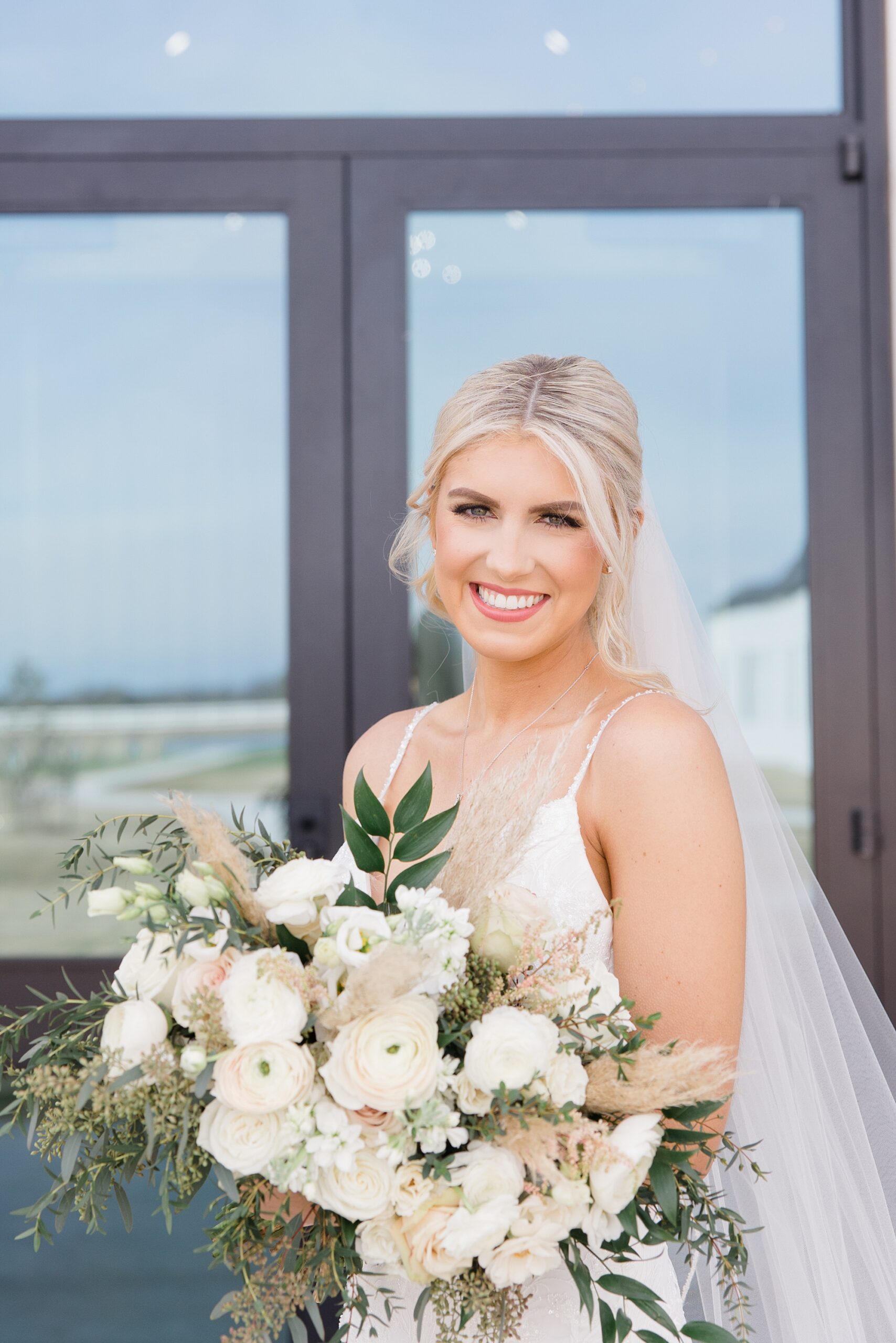 bride smiles holding bouquet in front of wedding gown 