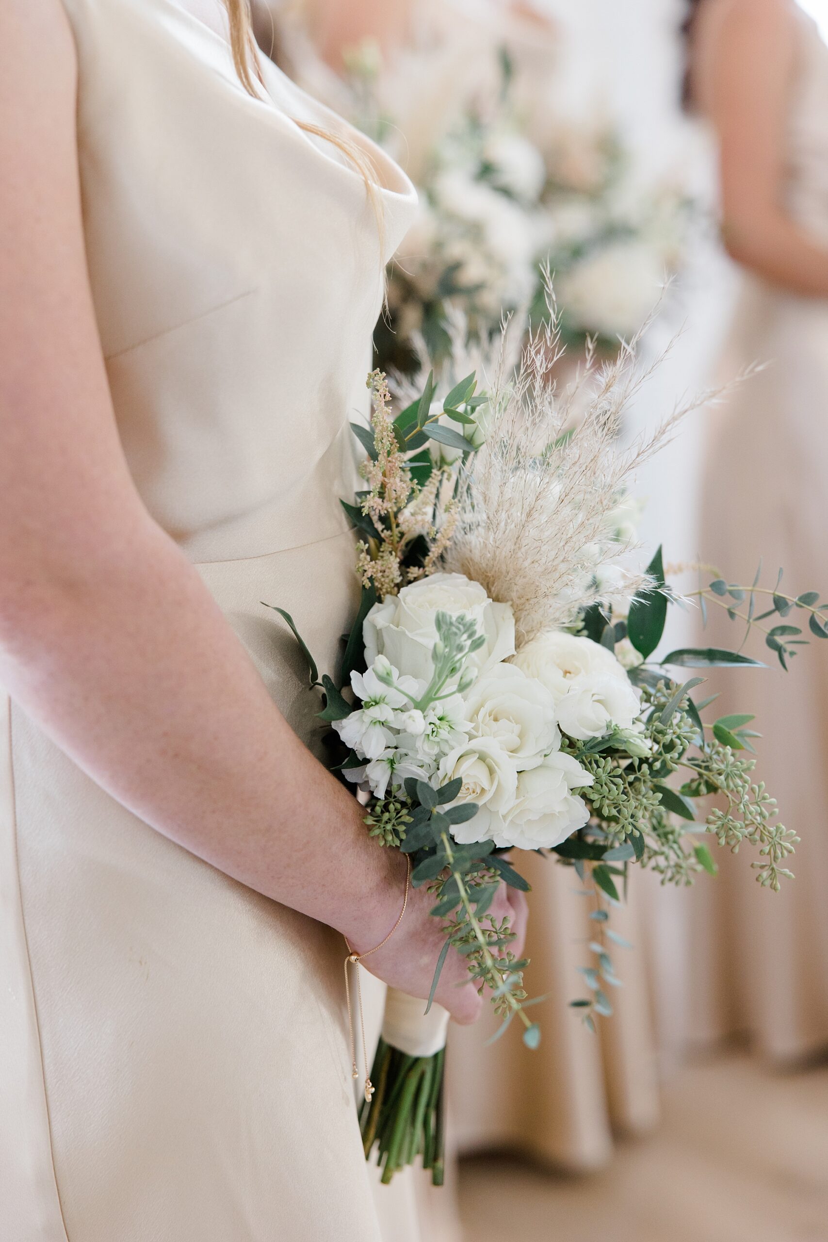 bridesmaid holds bouquet of white flowers with grass 