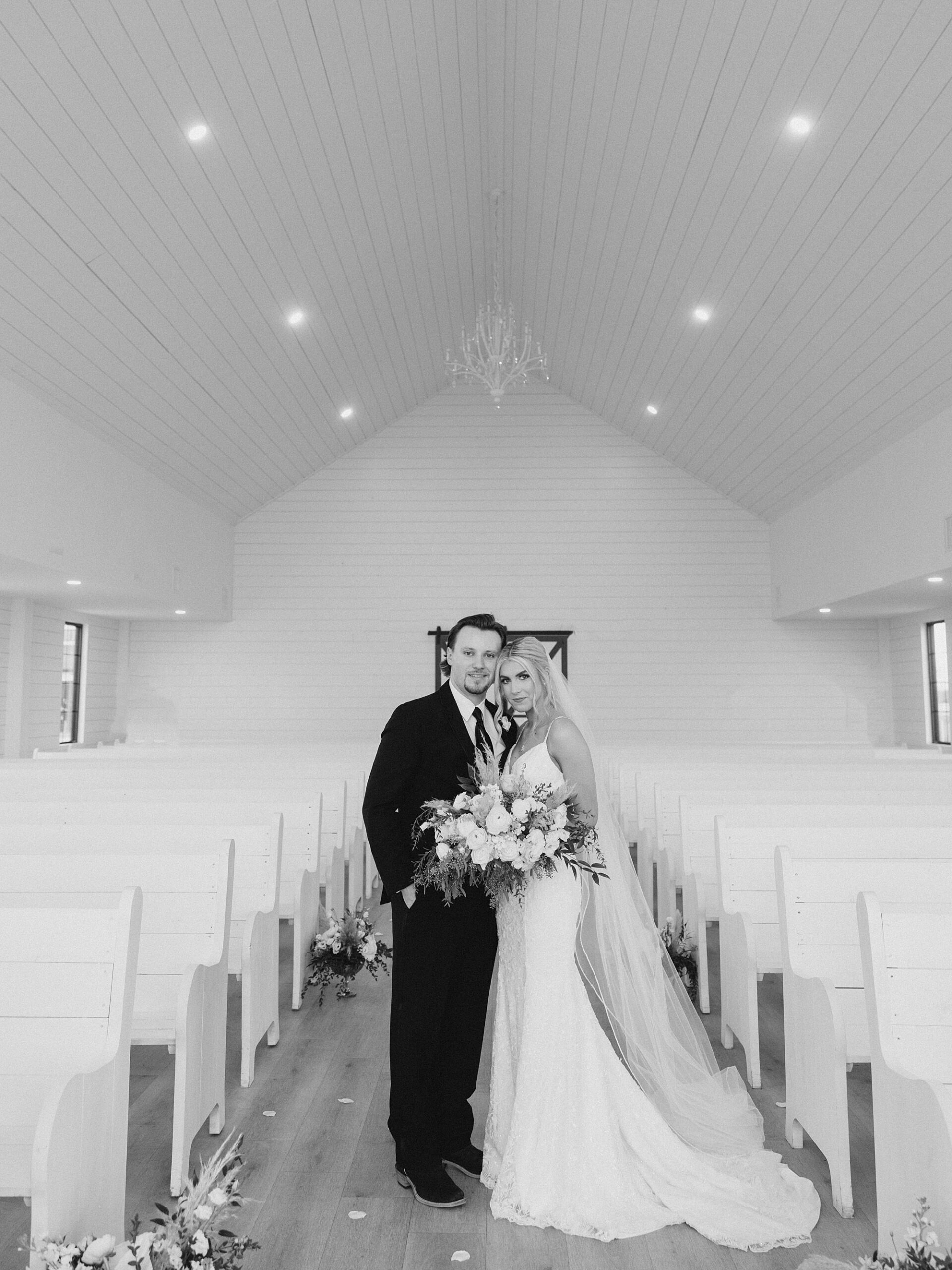 bride and groom hug in middle of pews in church 