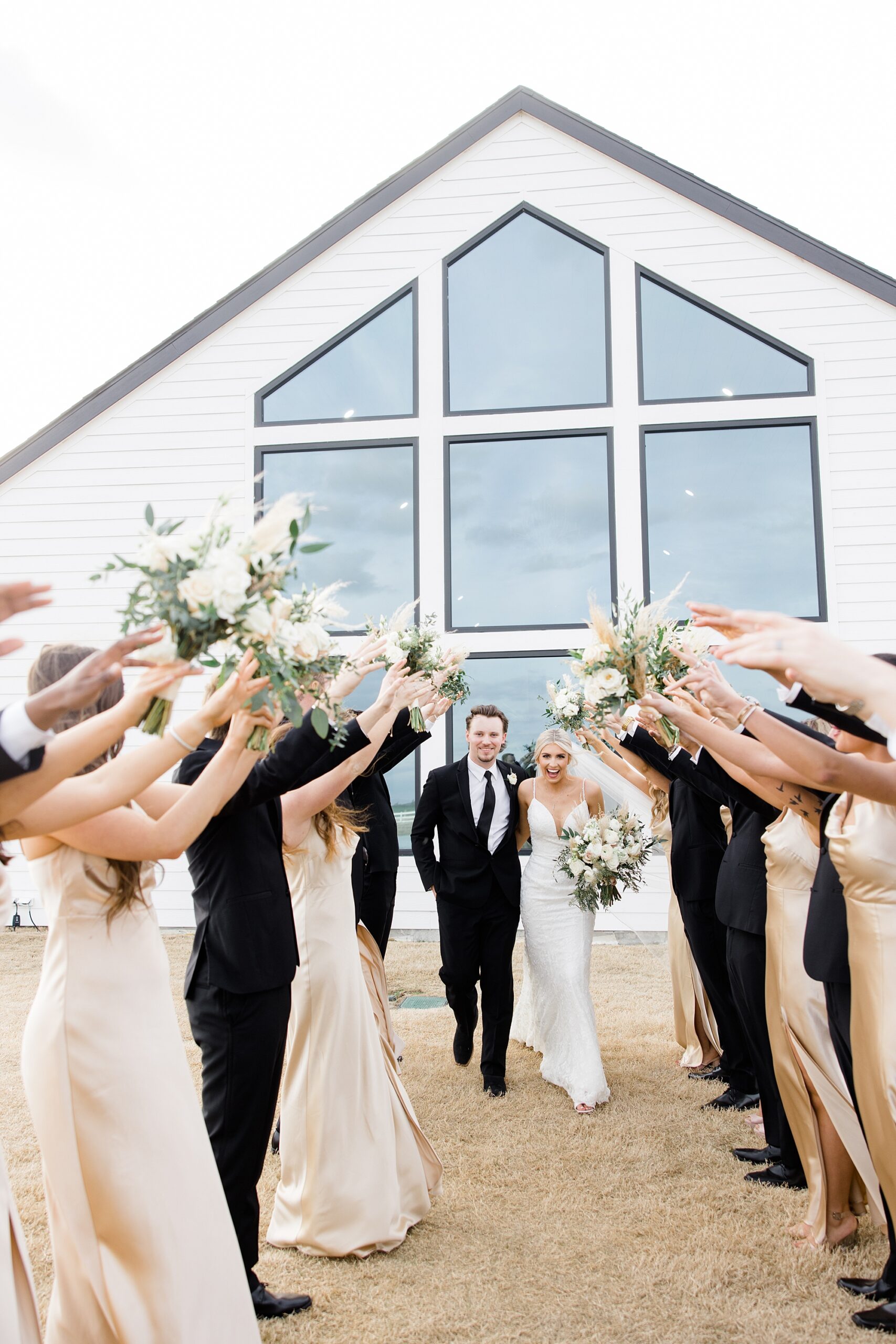 bride and groom walk under bridal party arms while cheering 