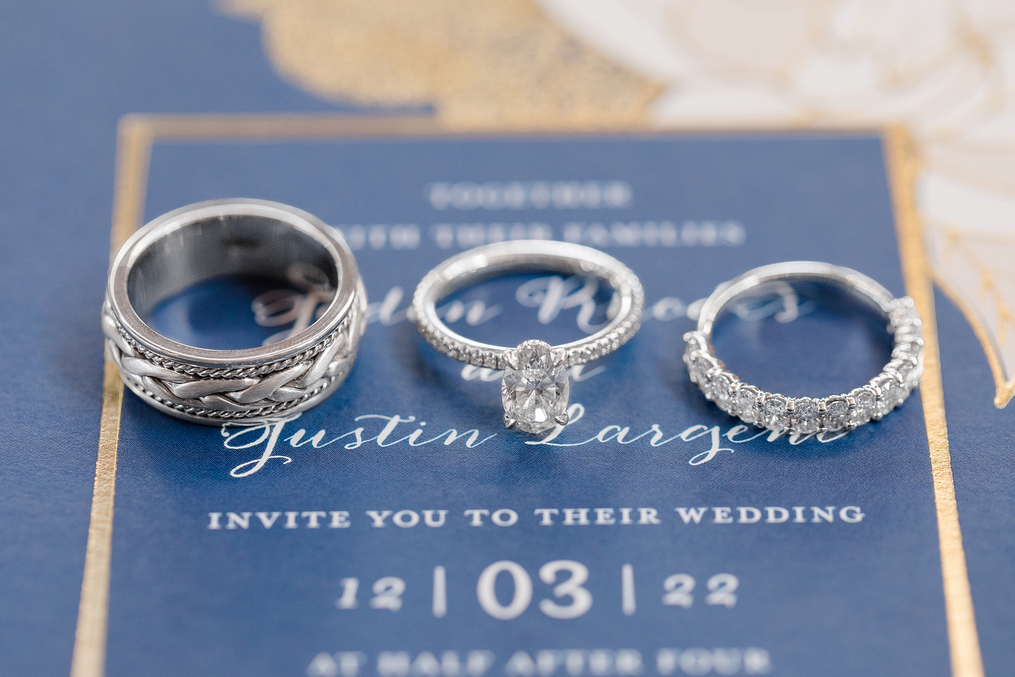 silver and diamonds rings rest on navy invitation 