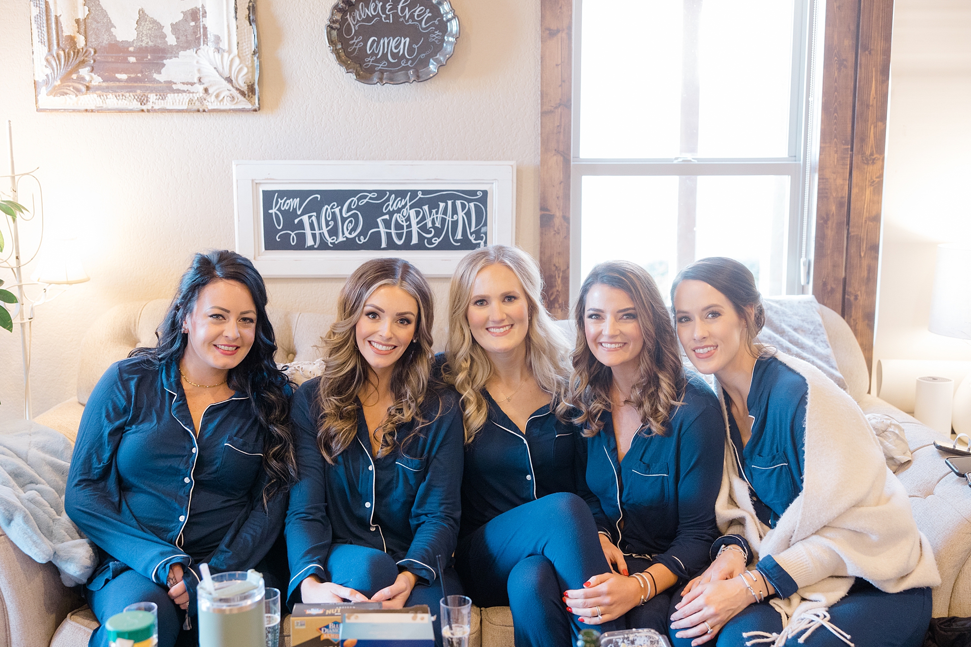 bride sits with bridesmaids in matching navy blue pajamas 