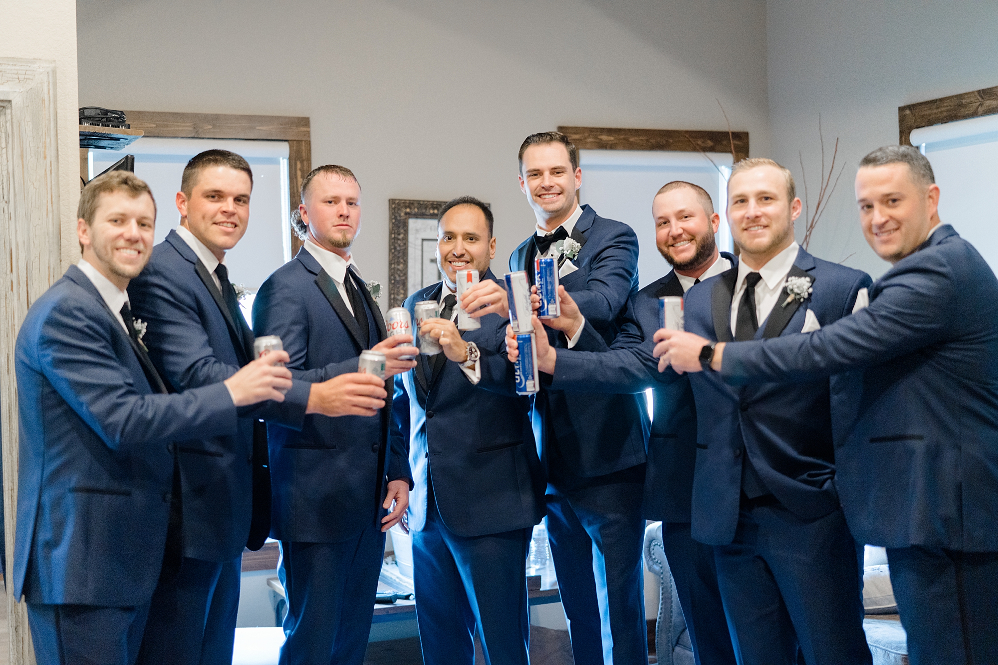 groom and groomsmen in navy suits toast drinks at The Brooks at Weatherford