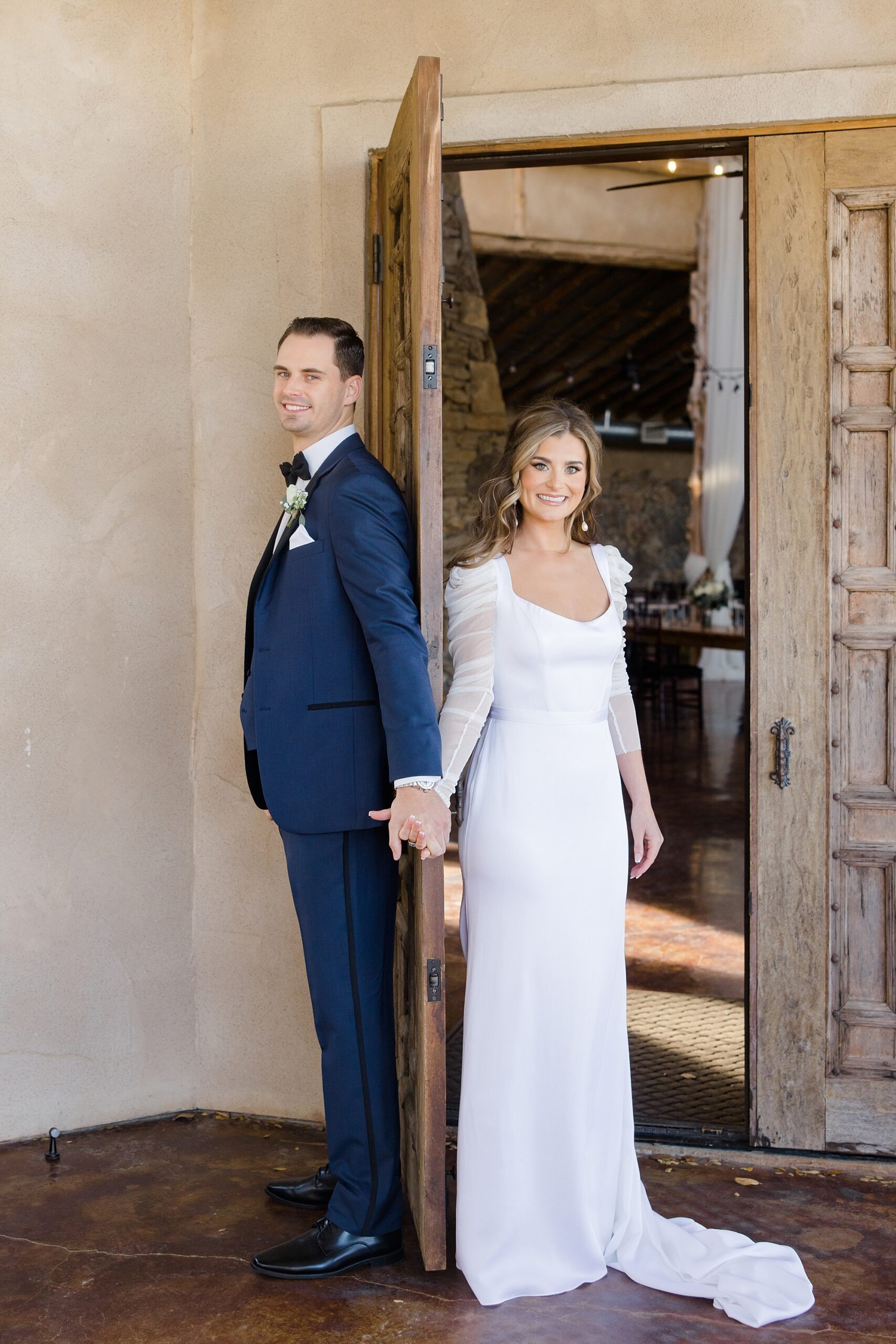 bride and groom hold hands around door during first touch 