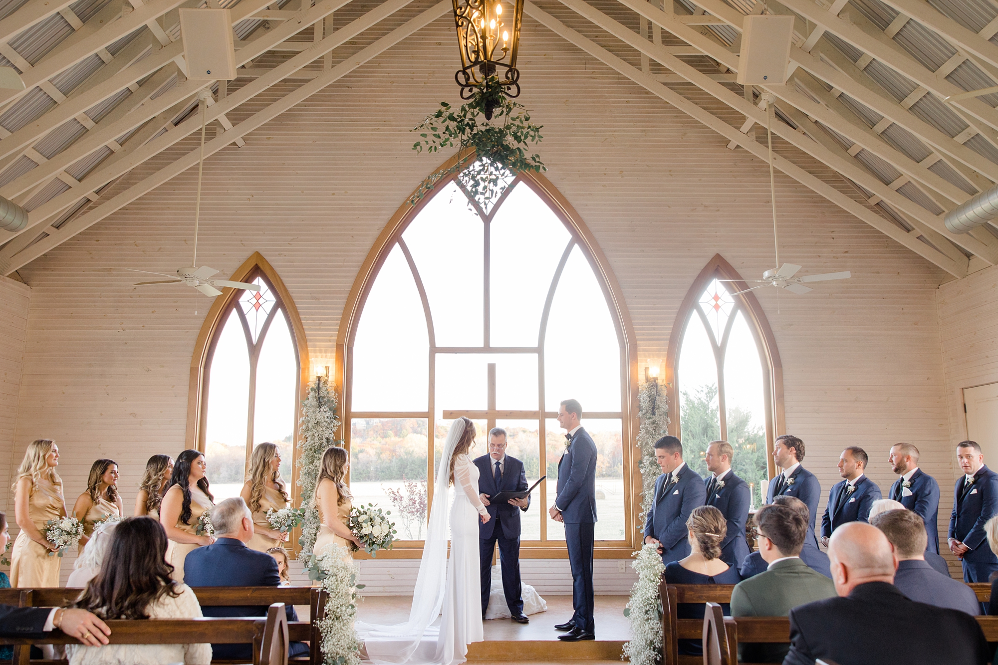 bride and groom stand at altar by large windows at The Brooks at Weatherford