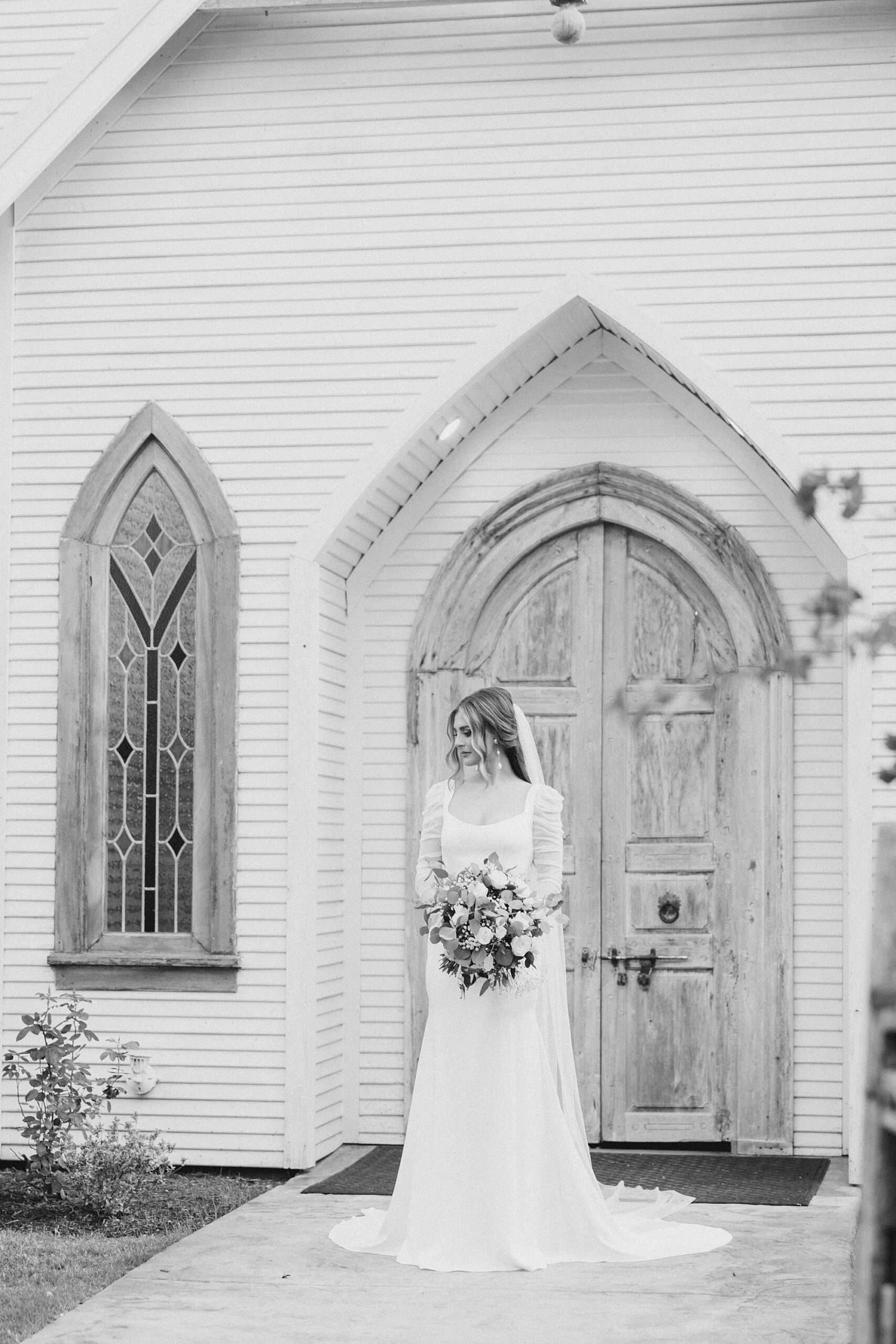 black and white portrait of bride standing outside chapel at The Brooks at Weatherford
